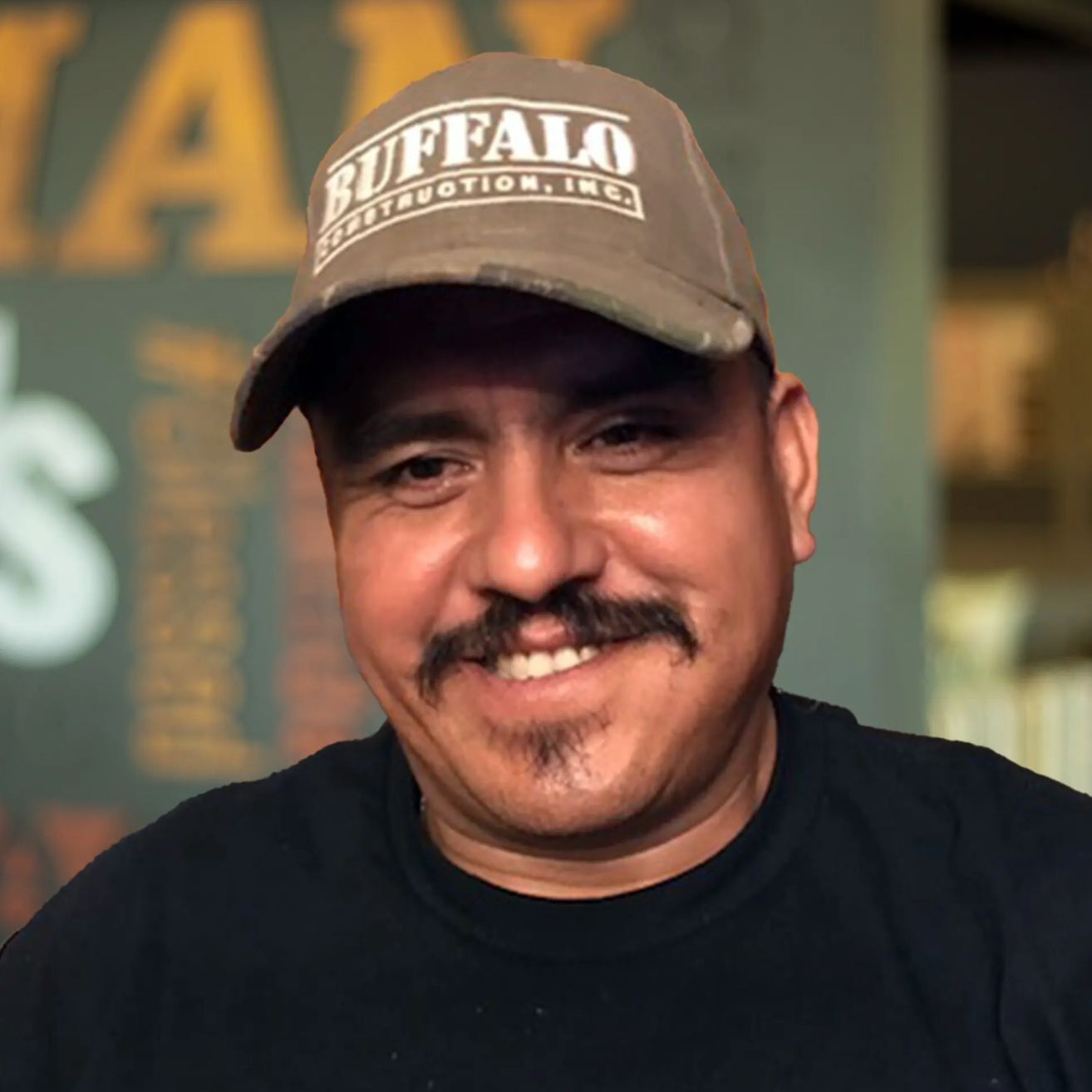 Val Rosales, smiling in front of a Buffalo-branded wall wearing a Buffalo Construction hat.
