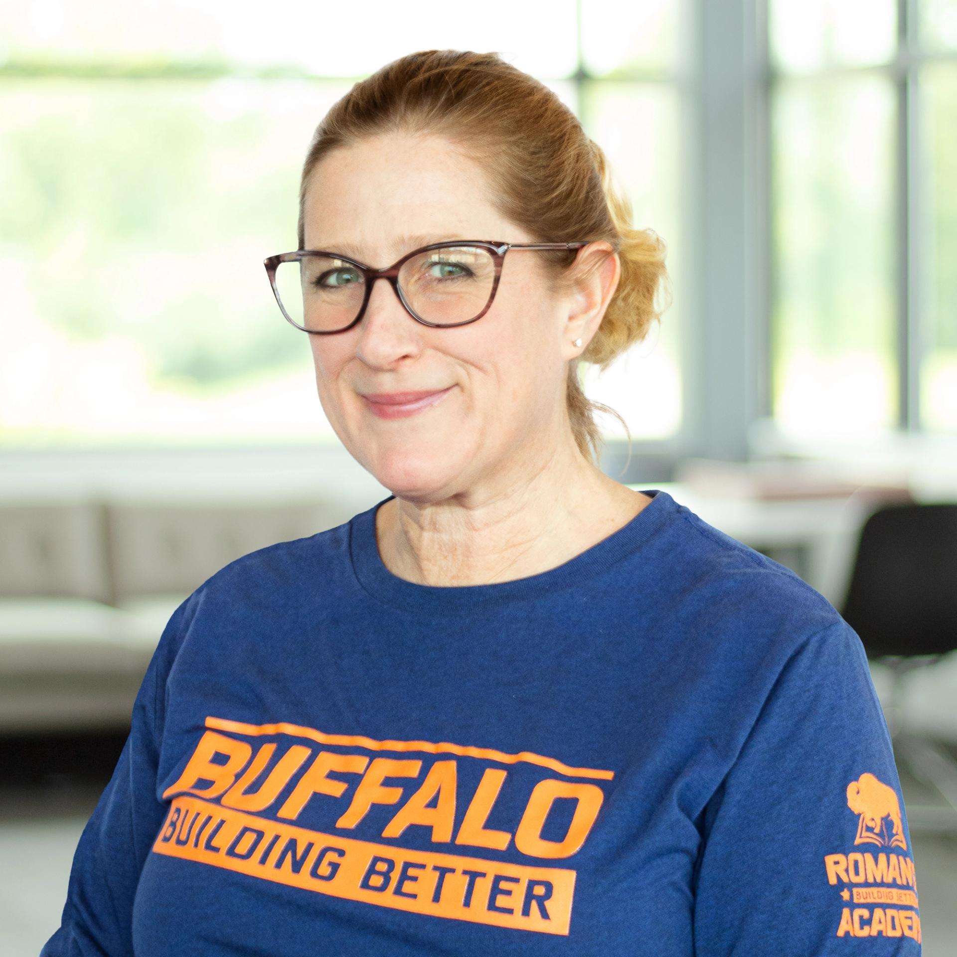 Rachel Steele wearing a buffalo branded shirt and smiling in a bright, modern office.