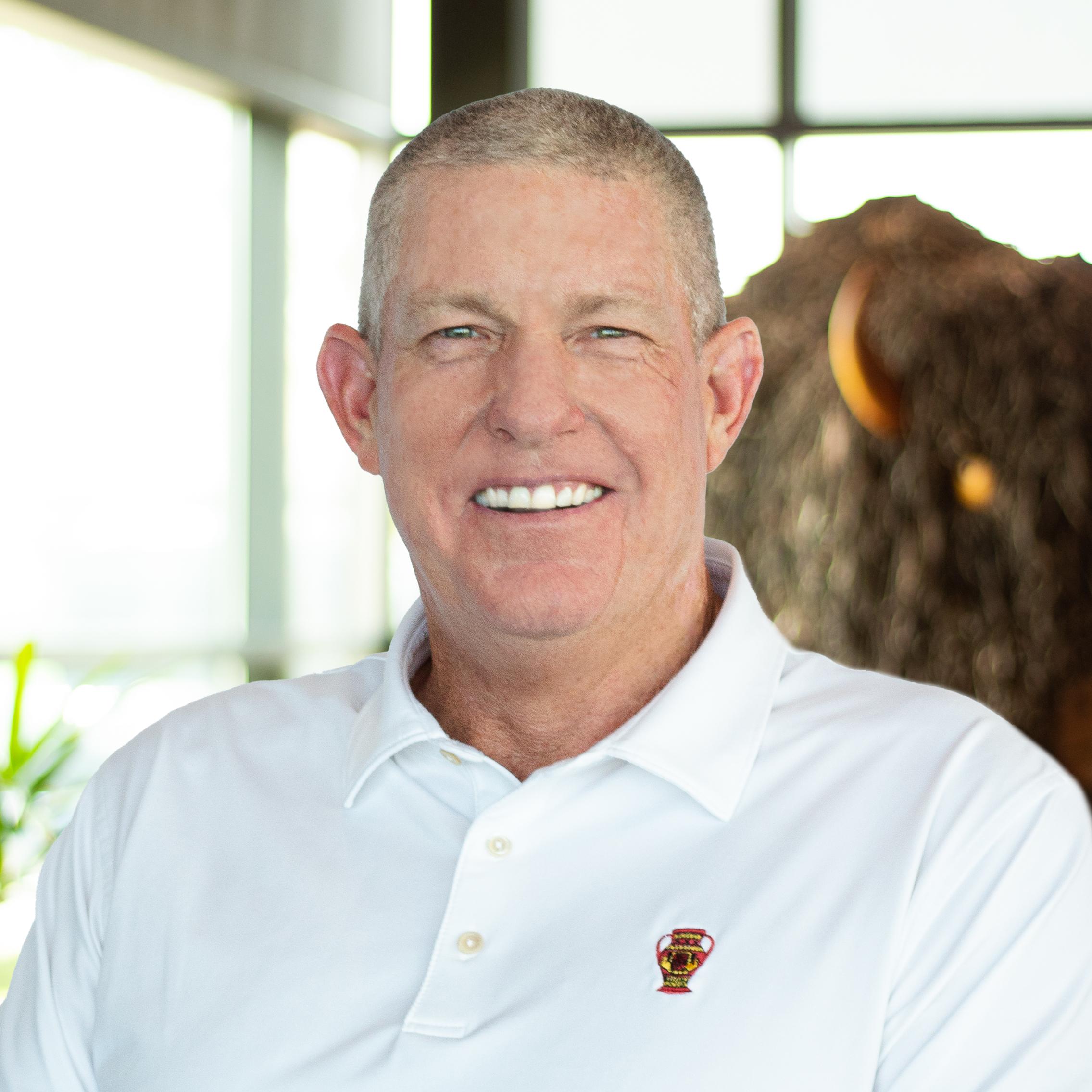 Scott Gregor smiling as he proudly stands in front of a statue of a buffalo.