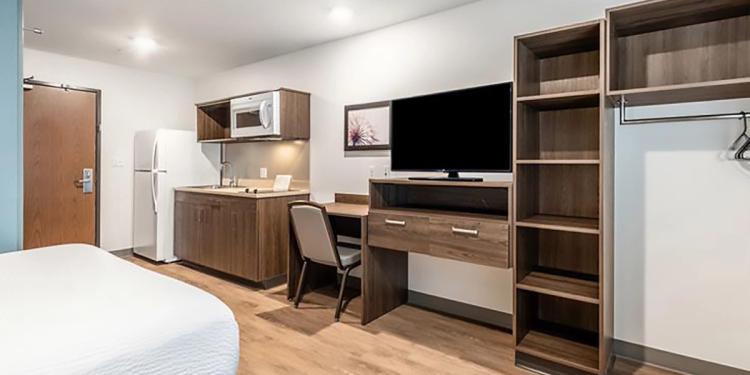 Guest TV, Desk, and kitchen amenities at the WoodSpring Suites hotel in Redlands, CA.
