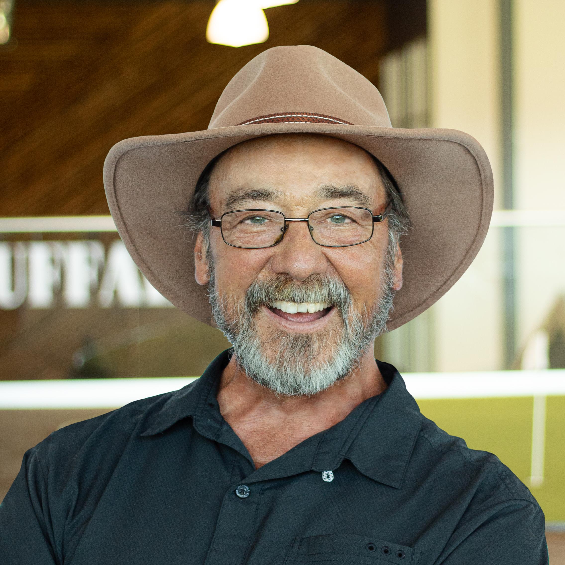 Dan Fellows with a big smile and cowboy hat, standing in buffalo's office space.