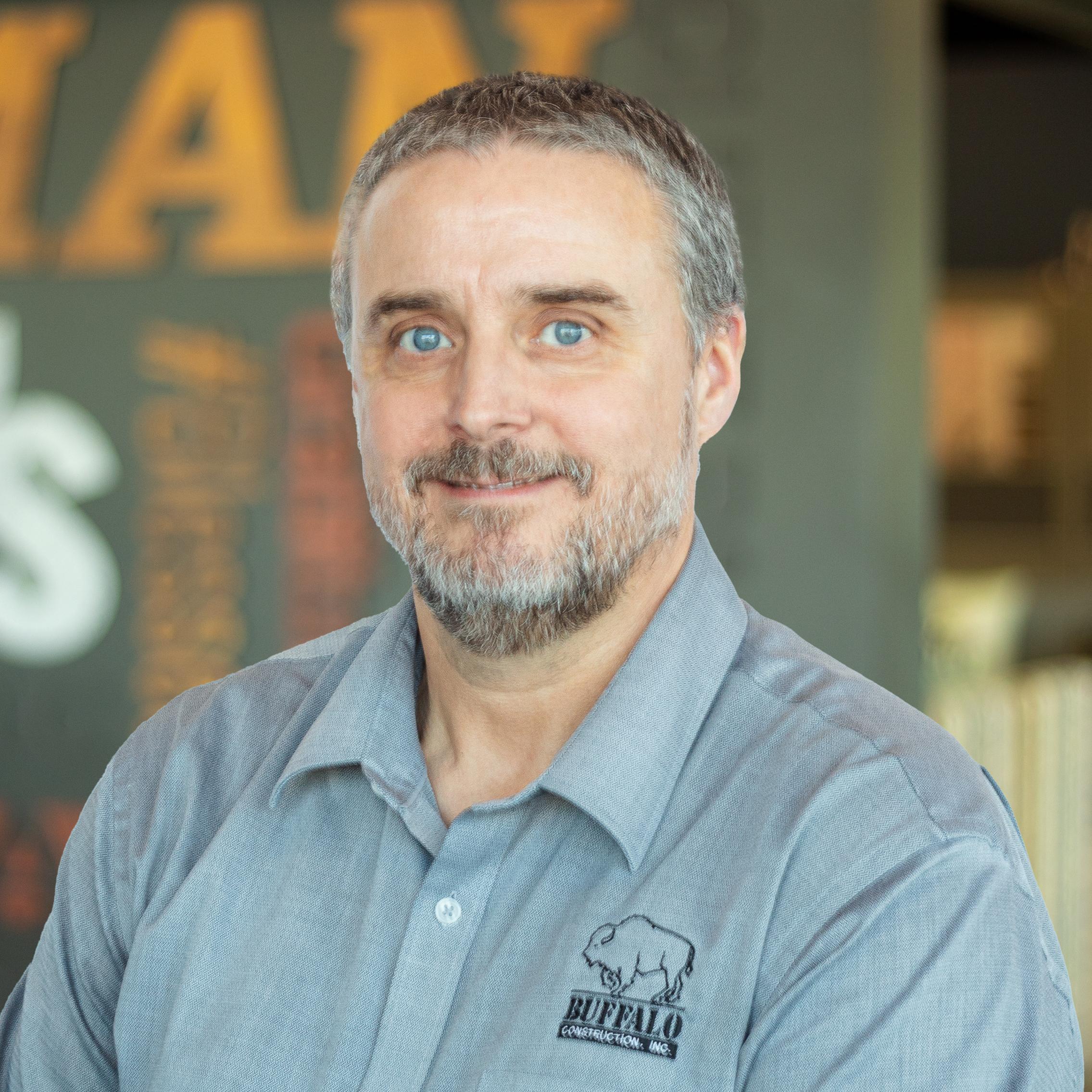 Mark Cassady wearing a buffalo branded button down and standing in front of a company-branded wall.