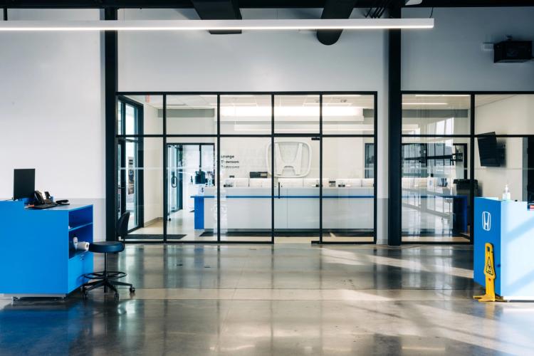 Finished service area looking through black-framed glass walls toward the completed Honda reception desk and customer entrance.