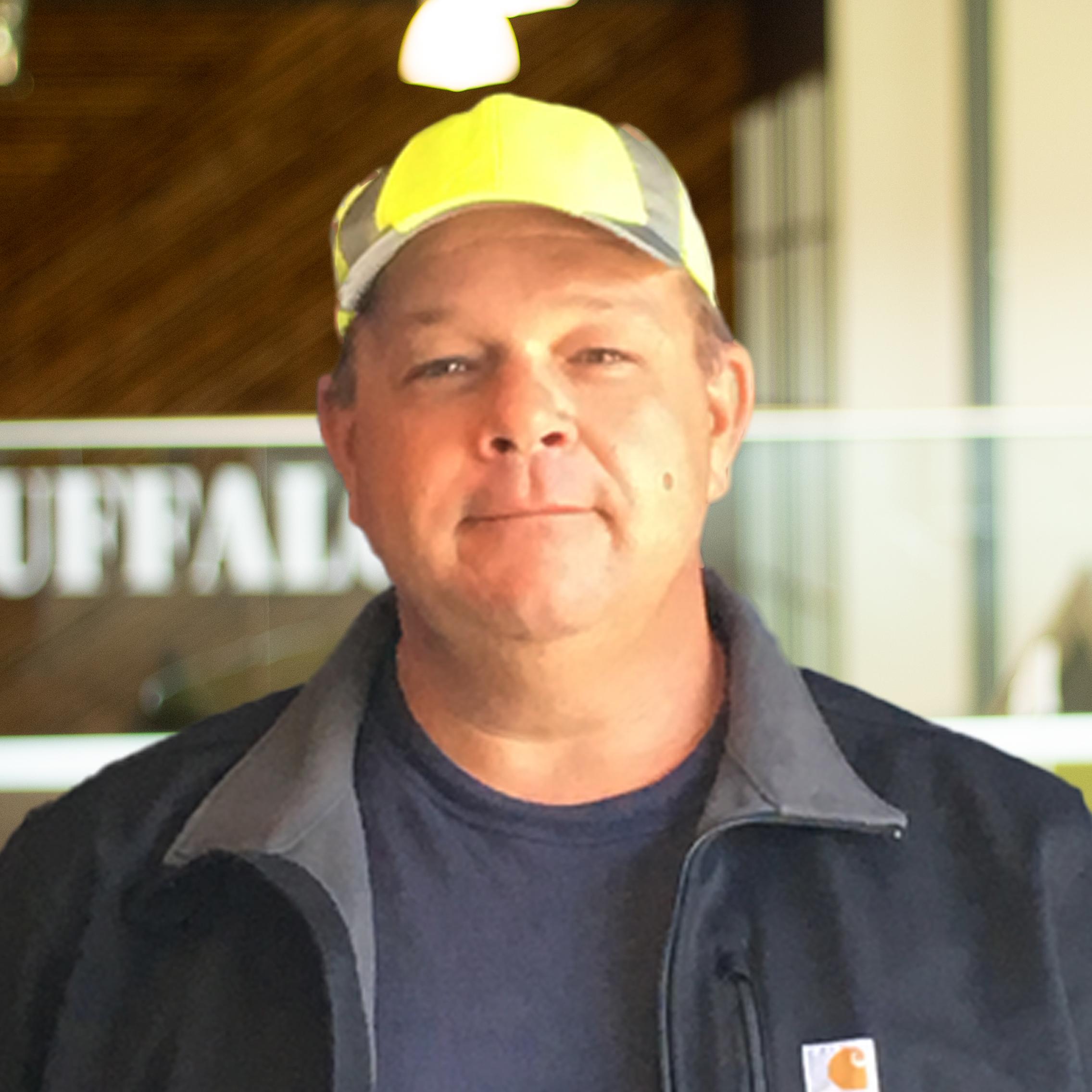 Damon Hourihan slightly smiling in a Carhartt jacket standing in buffalo's office space.