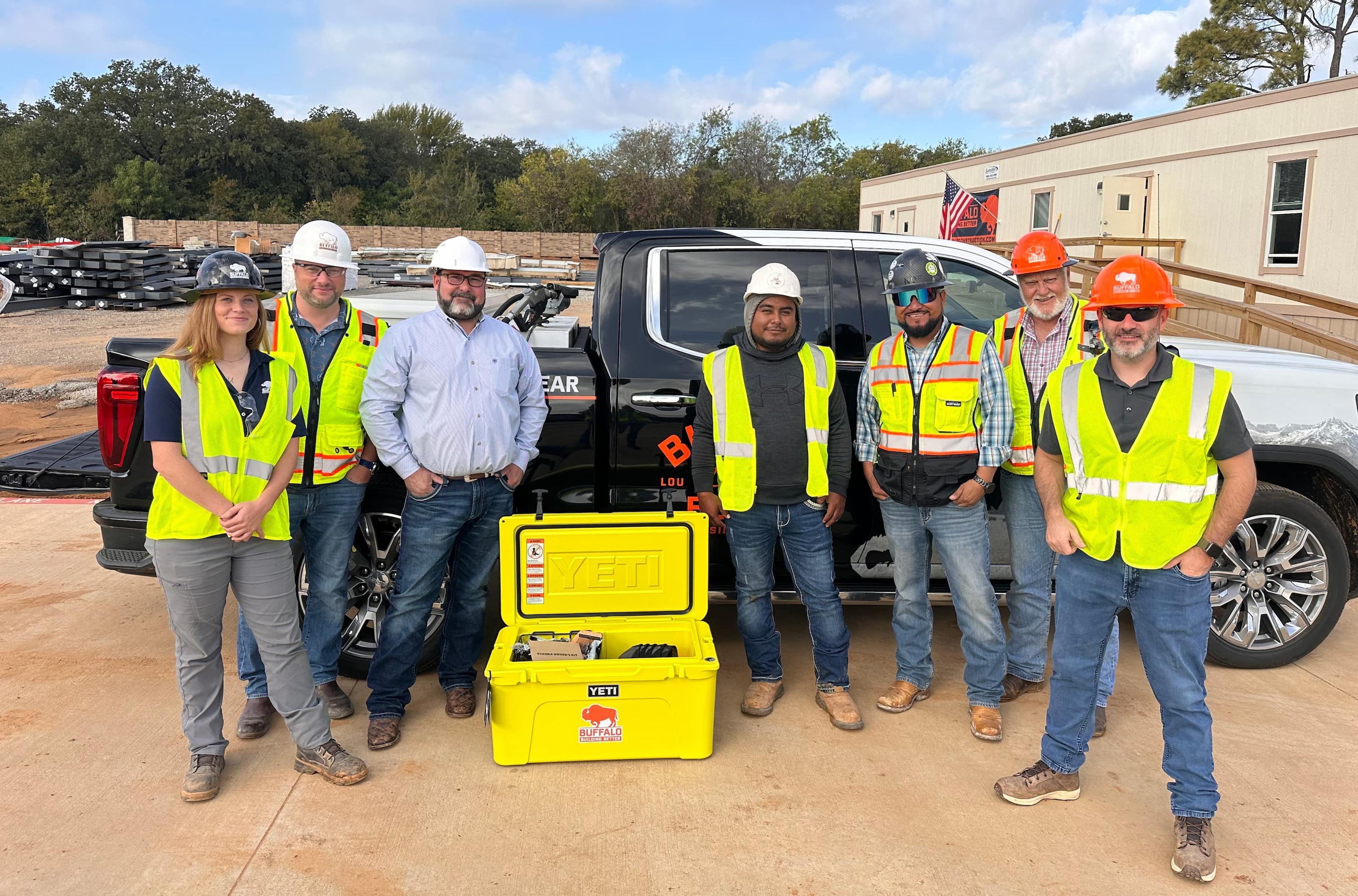 Superintendent and crew posing next to a yellow cooler at a job site