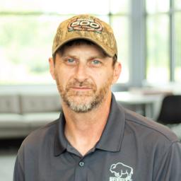 Travis Whitley wearing a buffalo branded polo and standing in a bright, modern office.
