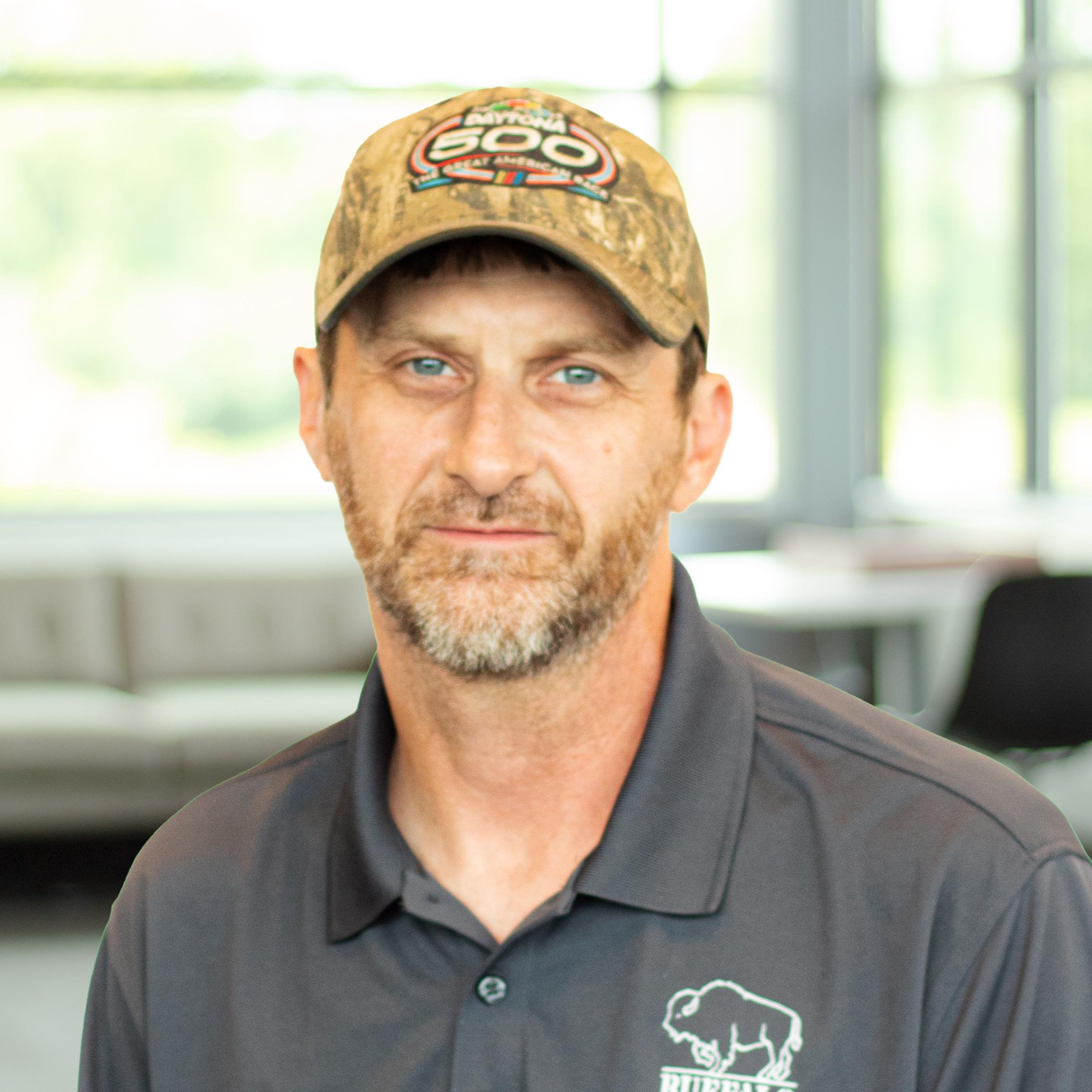 Travis Whitley wearing a buffalo branded polo and standing in a bright, modern office.