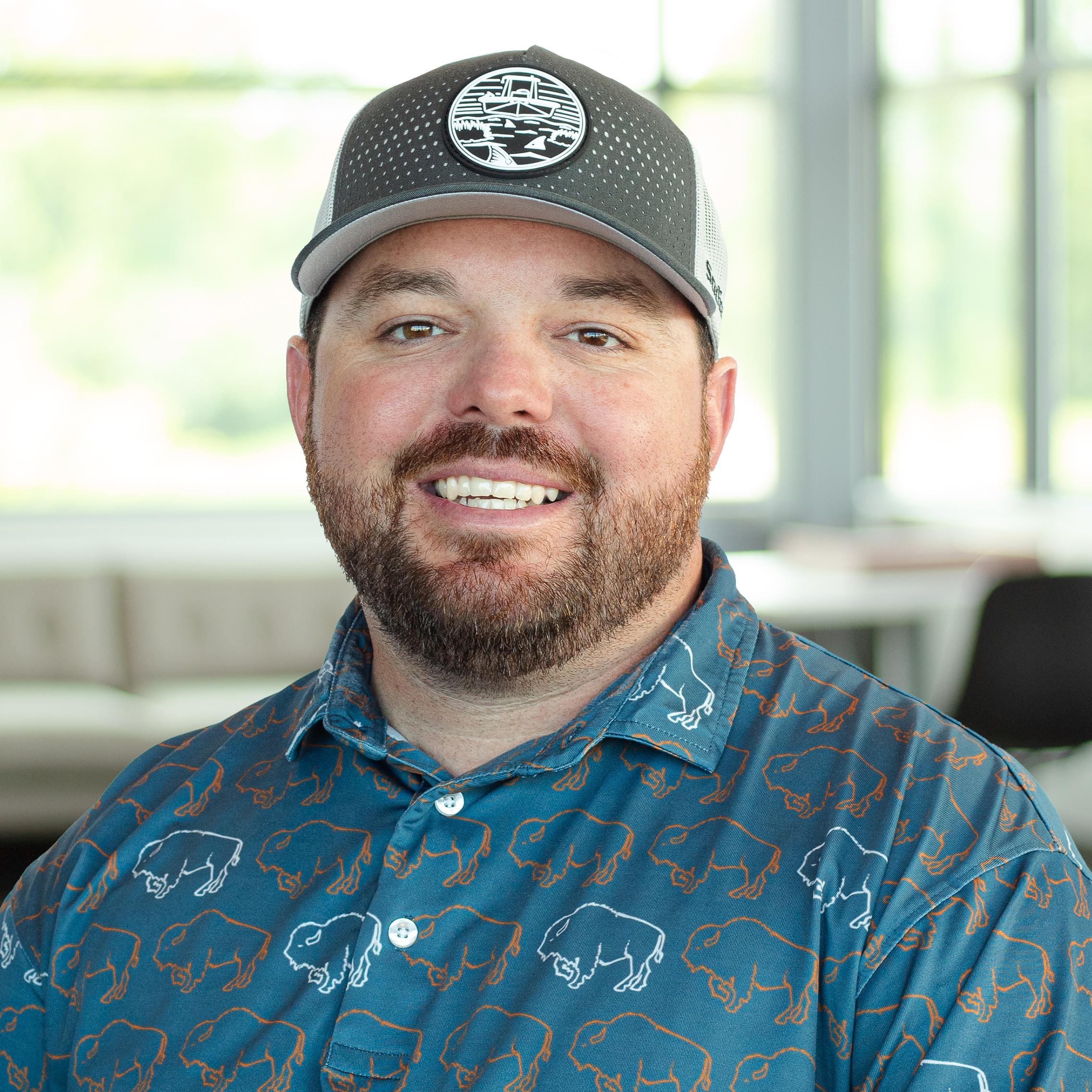 Chad Bruner wearing a buffalo branded polo and smiling in a bright, modern office.