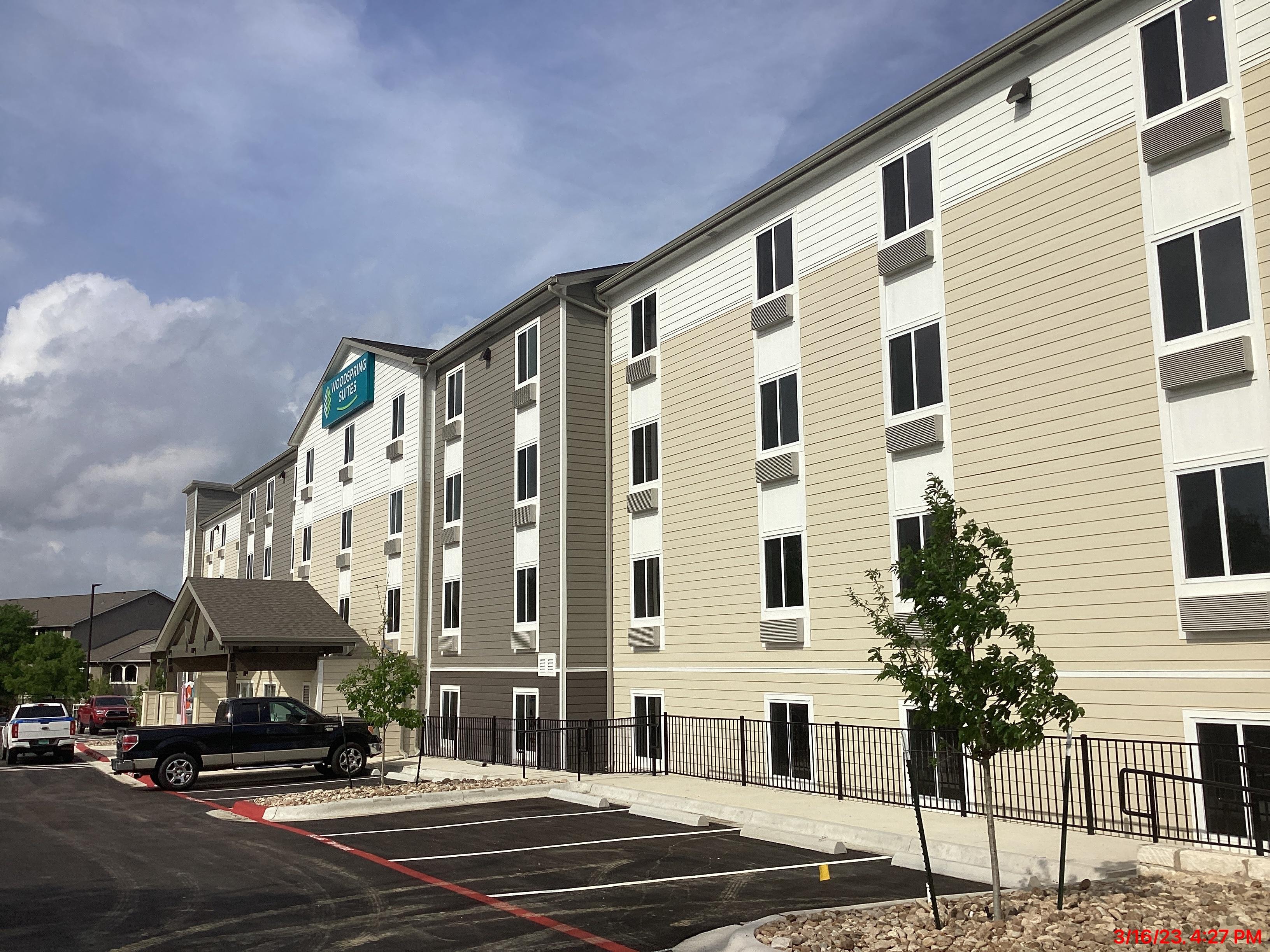 Exterior view of the front to the WoodSpring Suites hotel in Austin, TX.