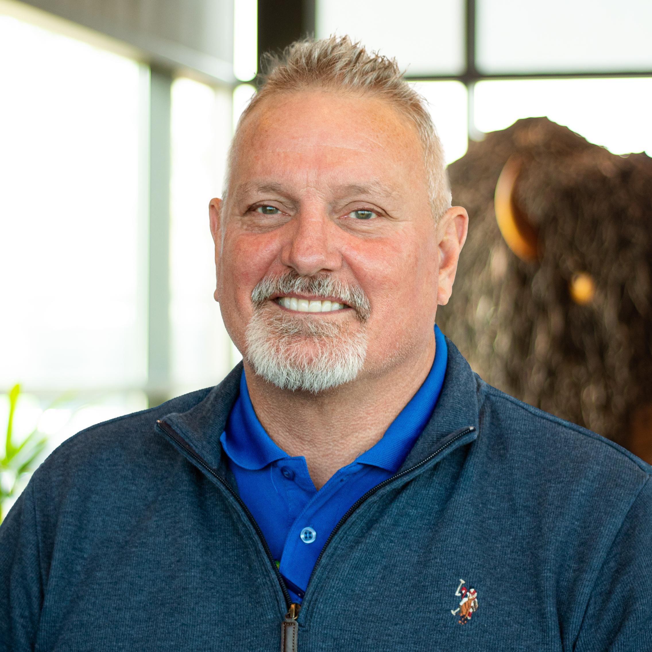Kevin Rambo smiling as they stand in front of a statue of a buffalo.