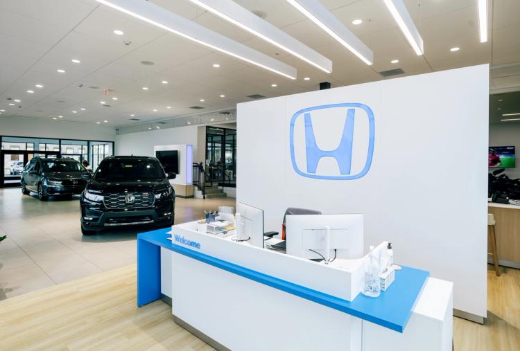 Completed Honda showroom welcome desk with blue accents, illuminated Honda branding and vehicles displayed in the background.