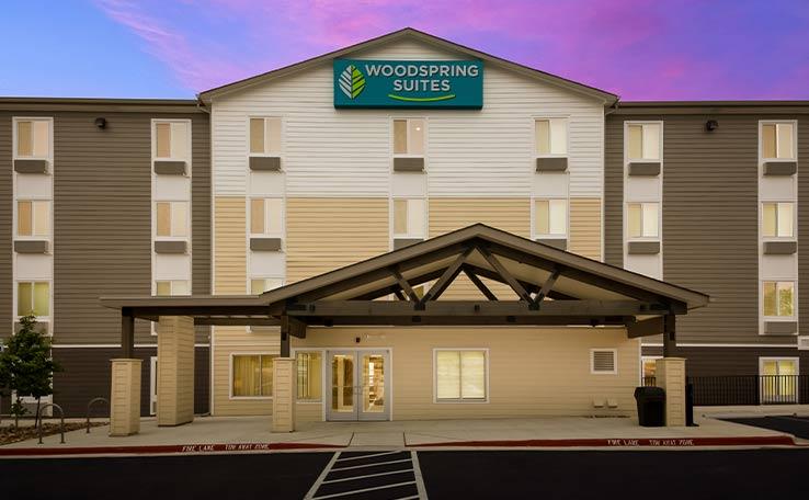 Exterior view of the front door to the WoodSpring Suites hotel in Austin, TX.