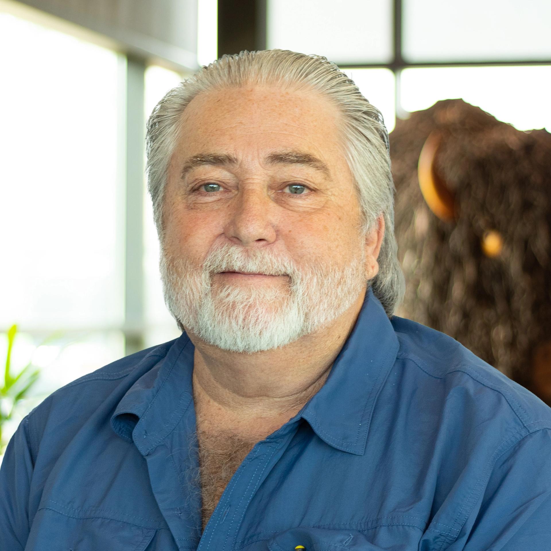 Randall Hendricks smiling as he stands in front of a statue of a buffalo.