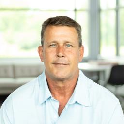 Art Glynn softly smiling in a bright, modern office.