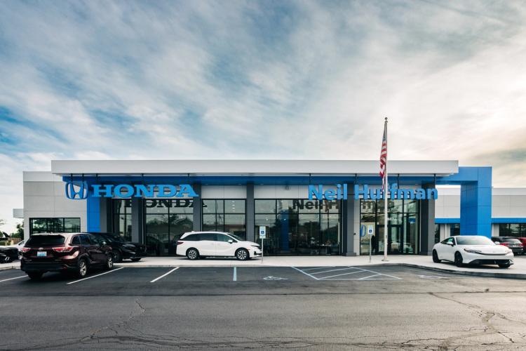 Completed front façade of Neil Huffman Honda with blue Honda branding, expansive showroom windows and vehicles displayed outside.