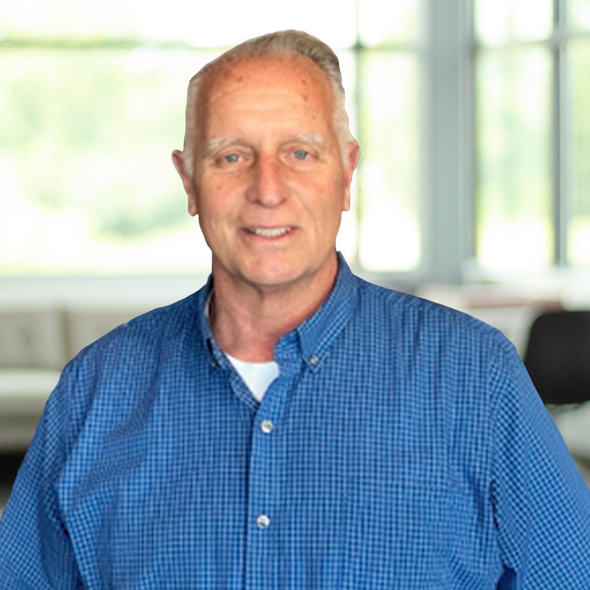 Joe Lewis with blue eyes wearing a blue button down, in a bright, modern office.