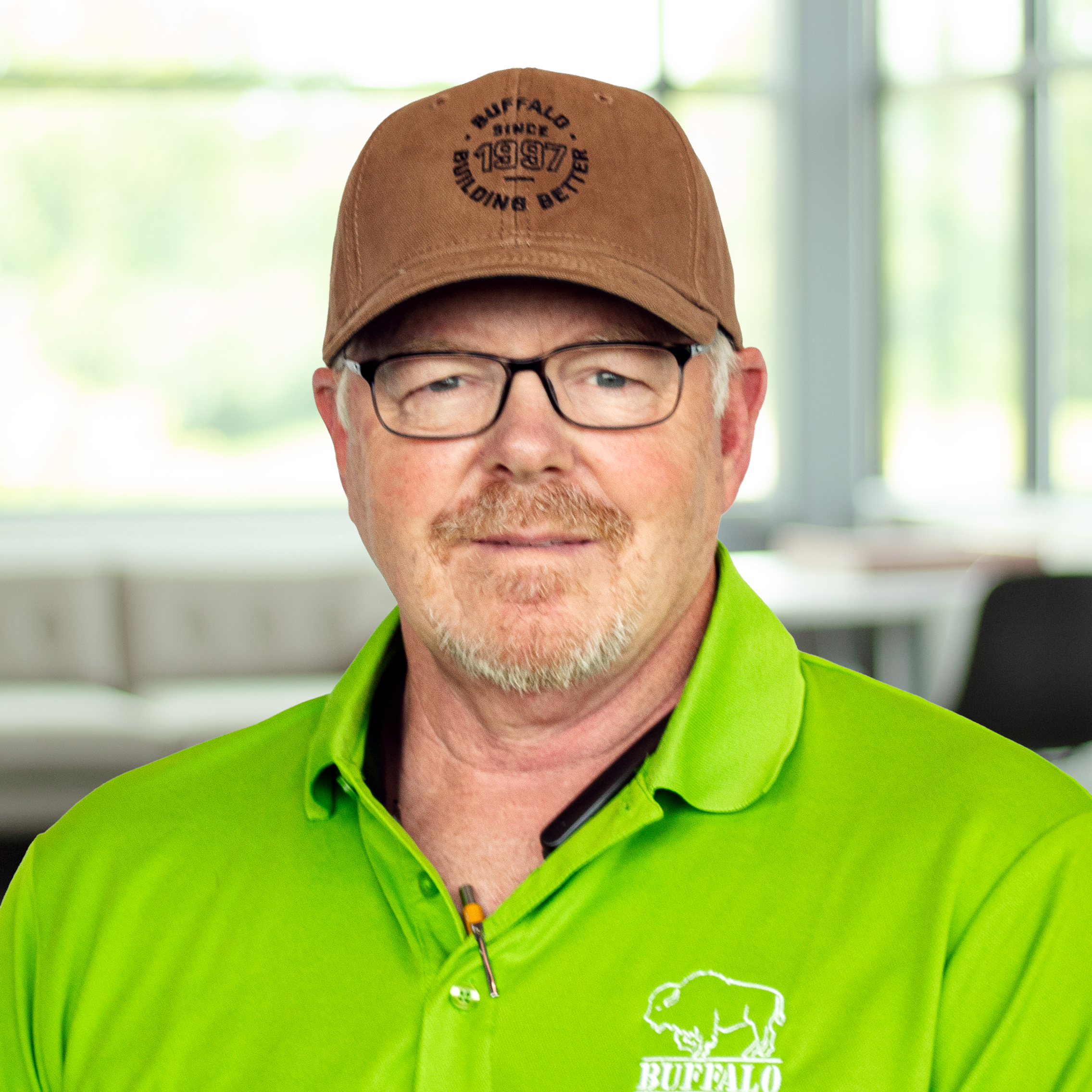 Keith Donoho wearing a bright green buffalo branded polo and smiling in a bright, modern office.