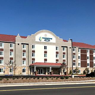 Exterior view facing the front of the WoodSpring Suites hotel in Redlands, CA.