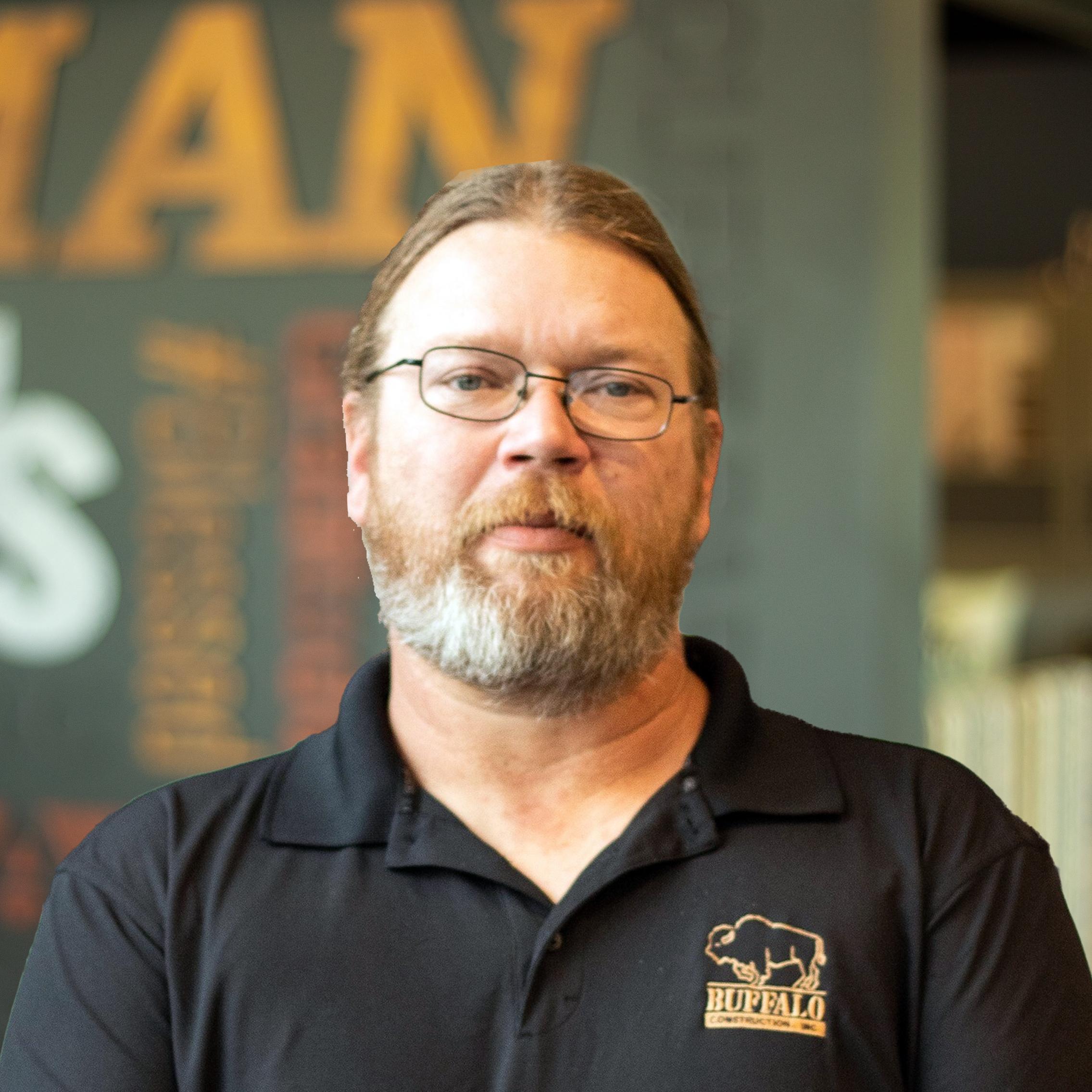 Bryan Pegg wearing a black buffalo branded polo and standing in front of a company-branded wall.