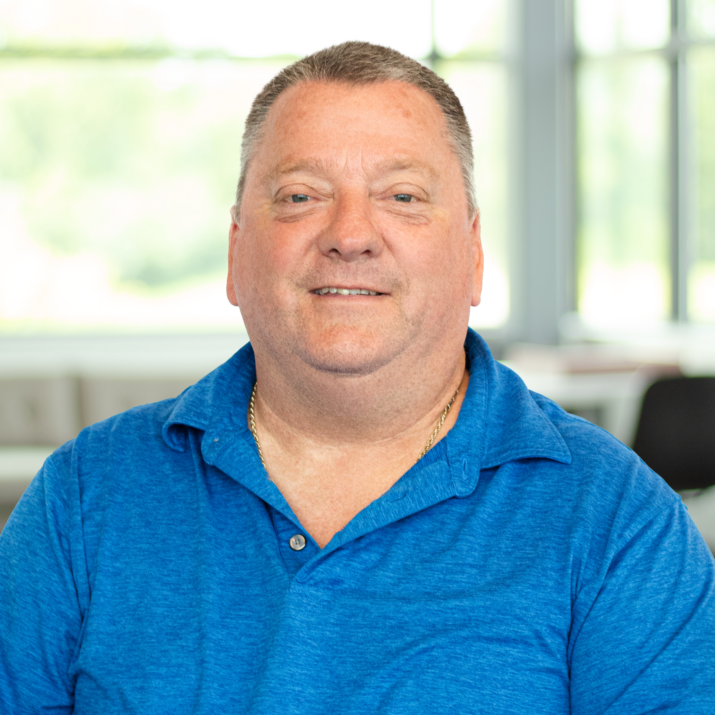 David Ovitt smiling and wearing a blue polo, in a bright, modern office.