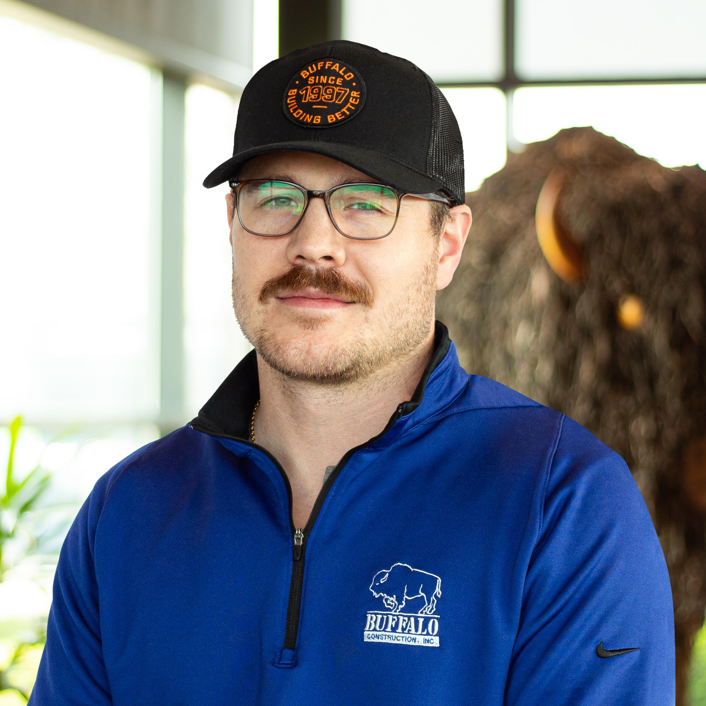 Carter Price smiling as they stand in front of a statue of a buffalo.