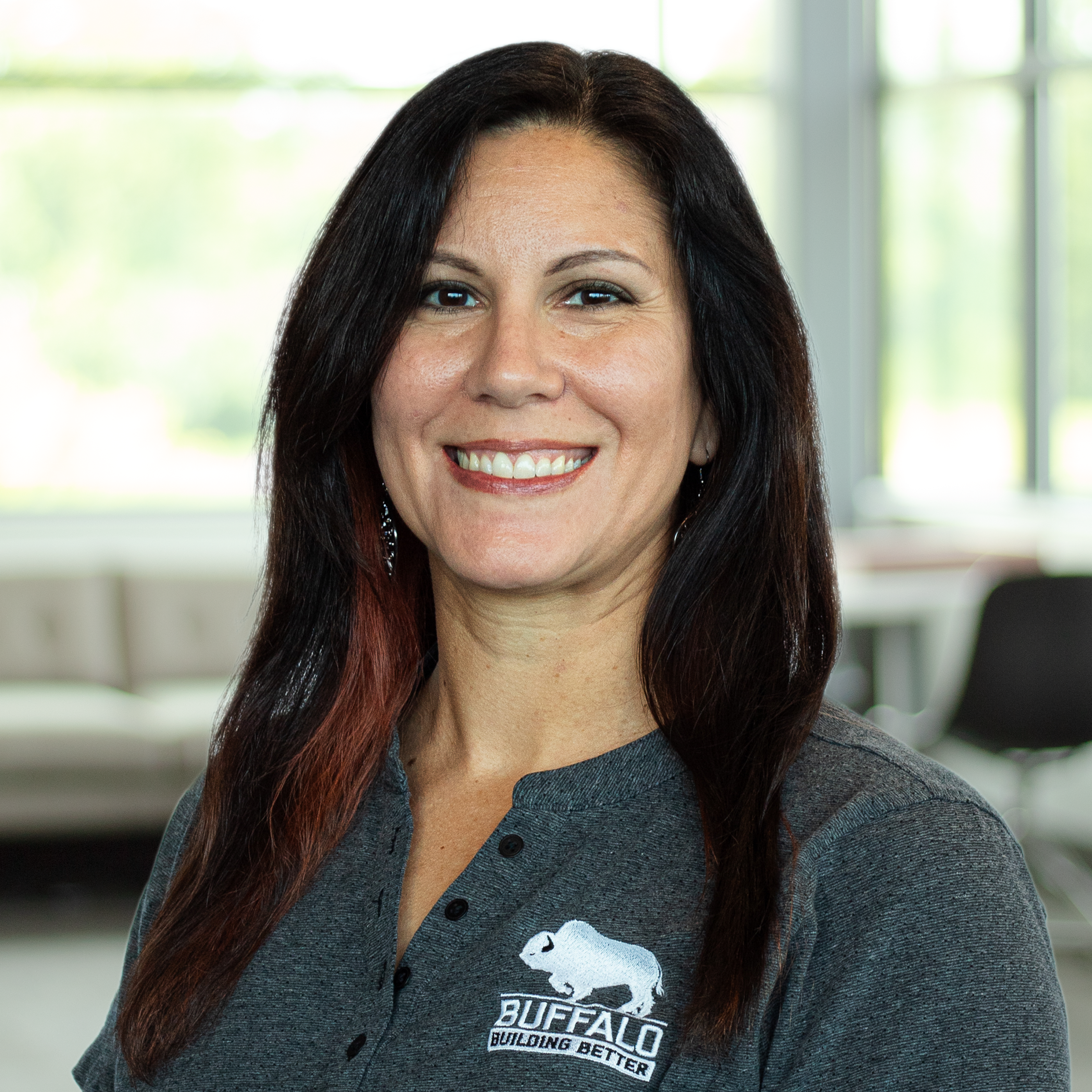 Kristin Bowman wearing a smile, standing in front of a modern office.