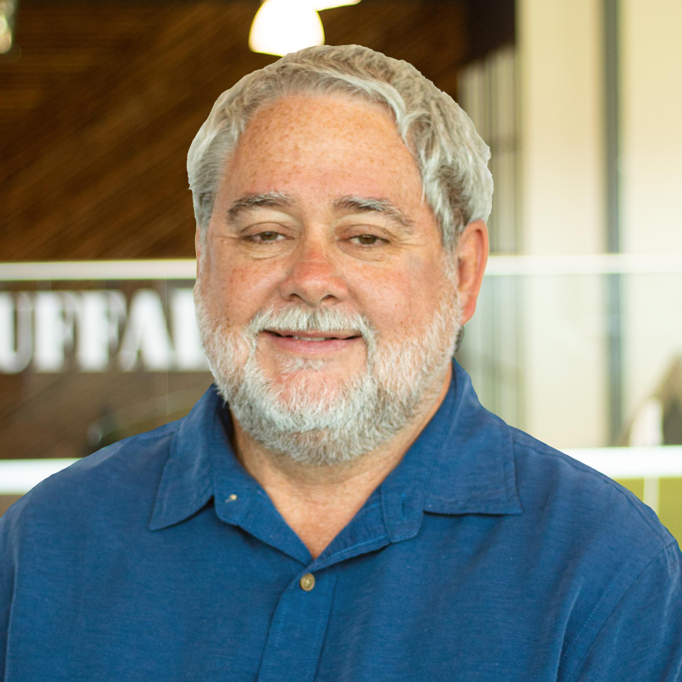 Robert Callahan smiling, wearing a blue button down and standing in buffalo's office space.