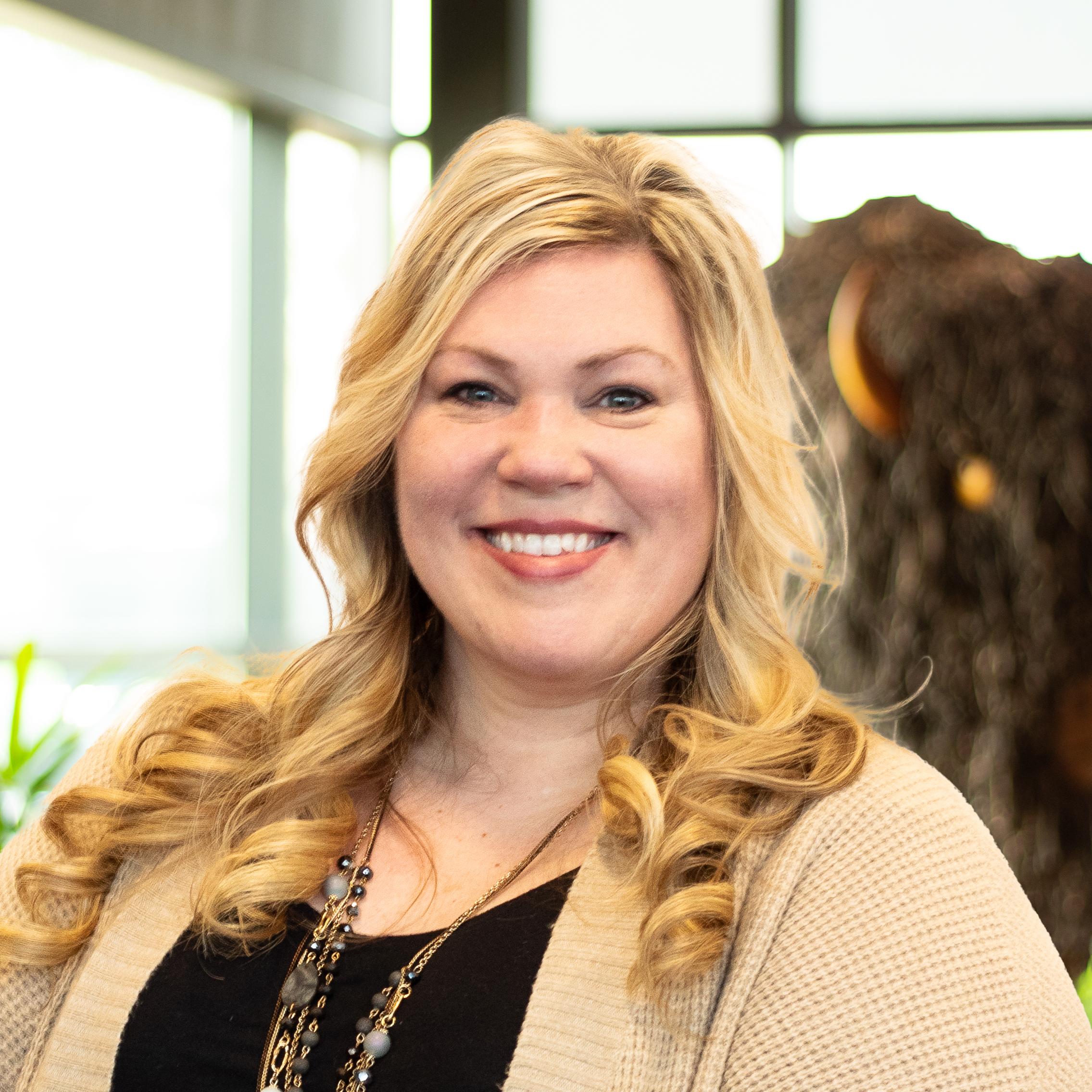 Mindy Montfort smiling as she stands in front of a statue of a buffalo.