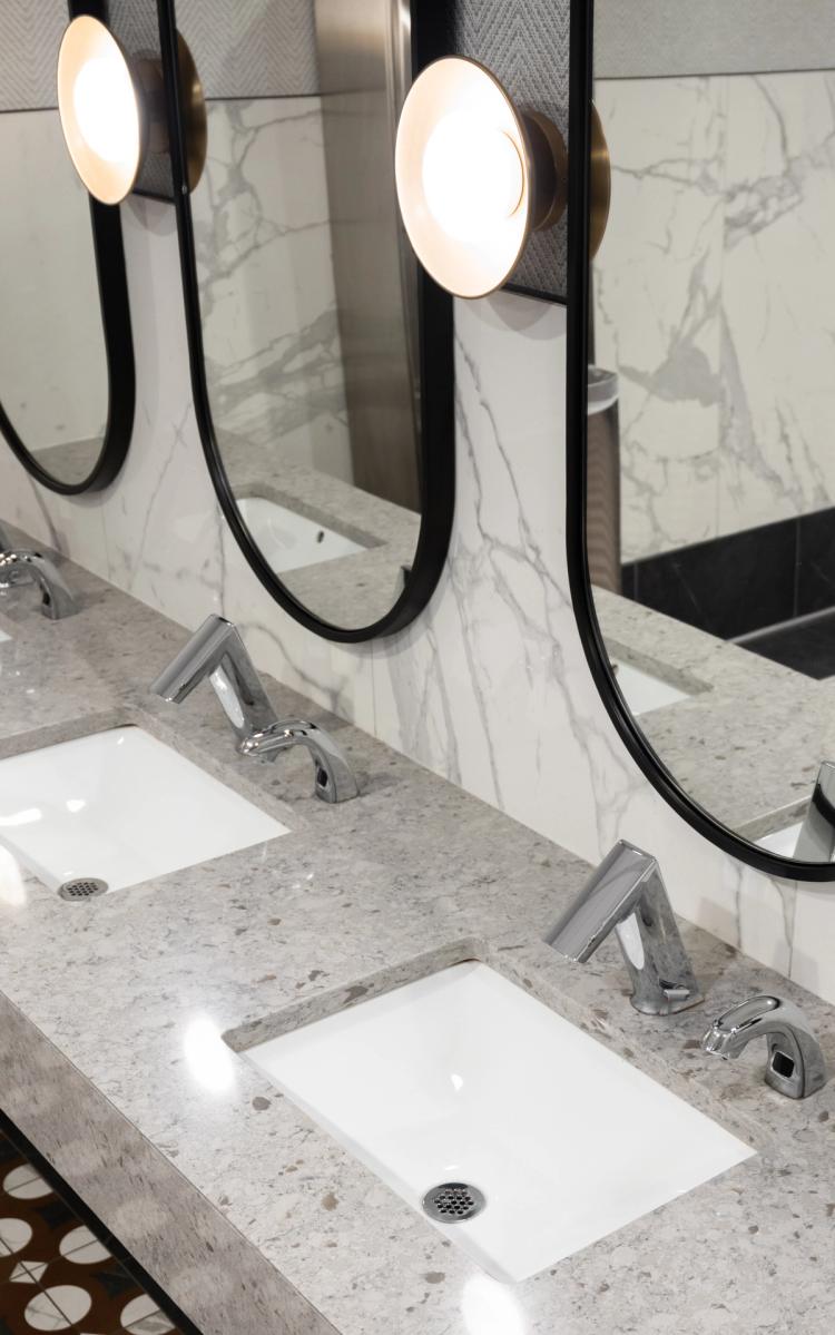 Marble vanity with modern faucets and oval mirrors