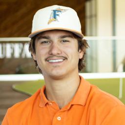 Dakota Forish smiling, wearing a bright orange polo , standing in buffalo's office space.