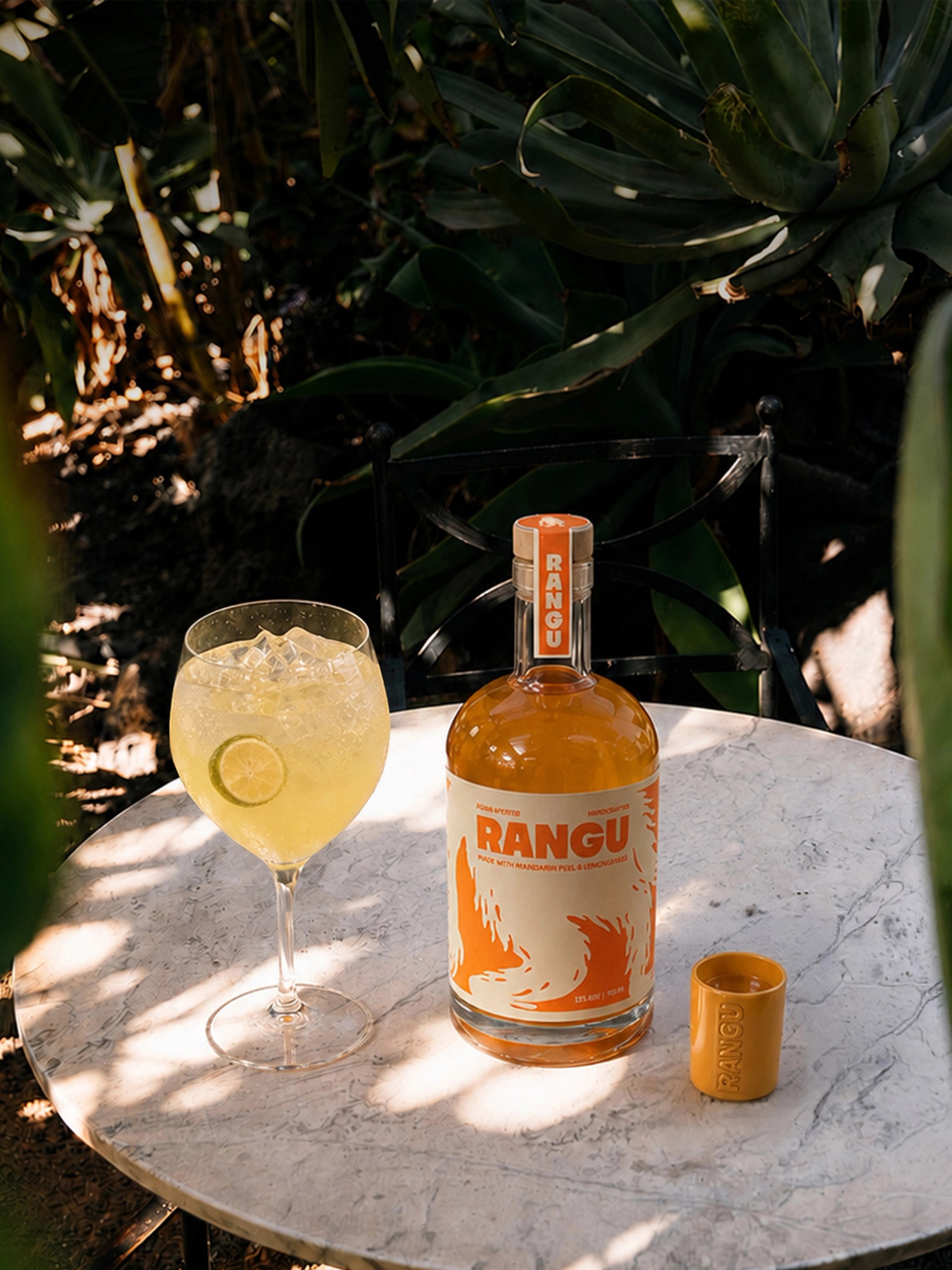 Rangu bottle on a table under palm leaves at golden hour