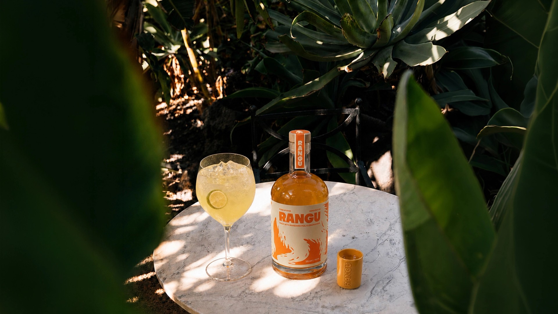 Rangu bottle on a table under palm leaves at golden hour