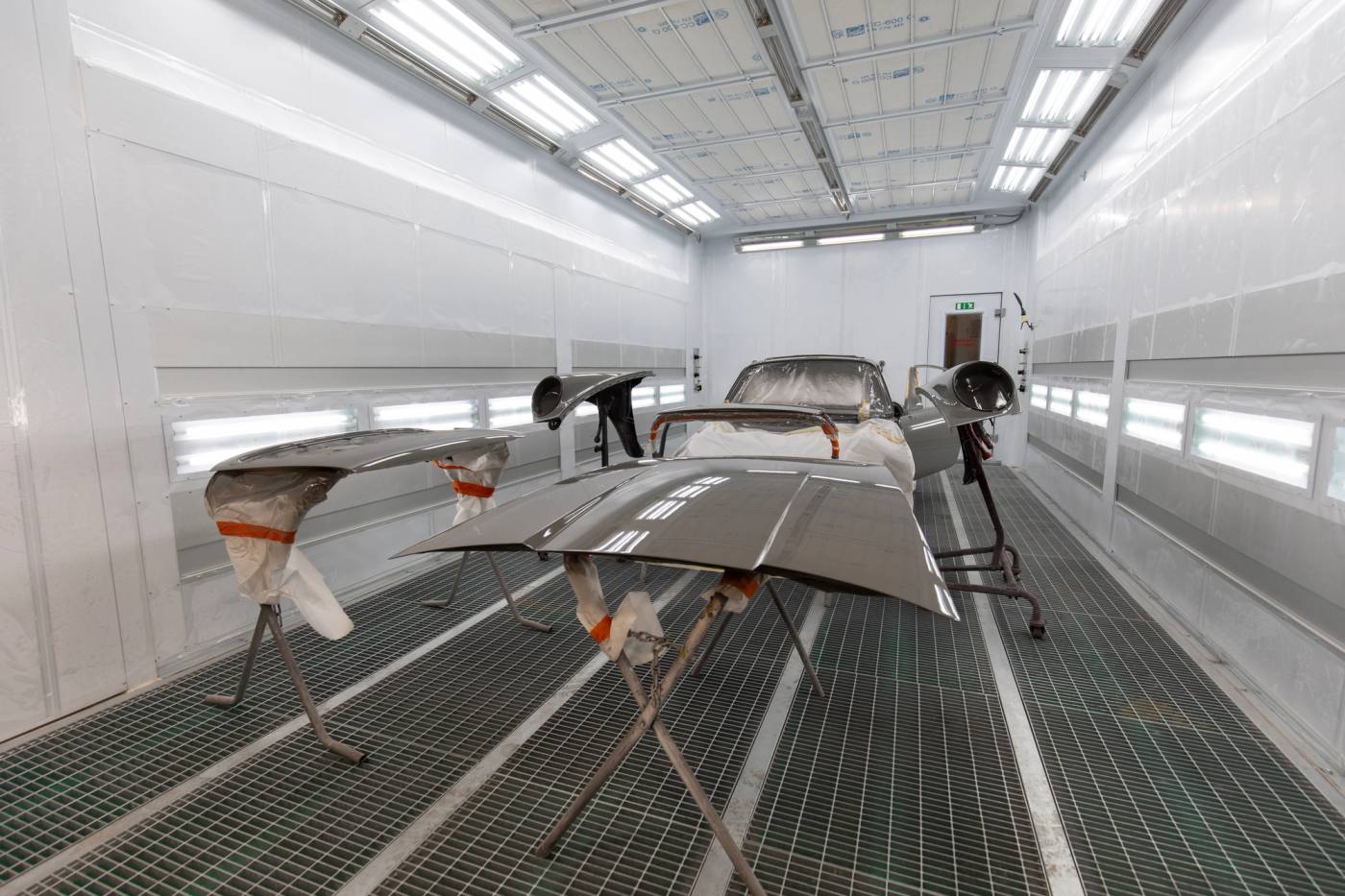 Vehicle panels off the car on stands in a Carl's Collision spray booth