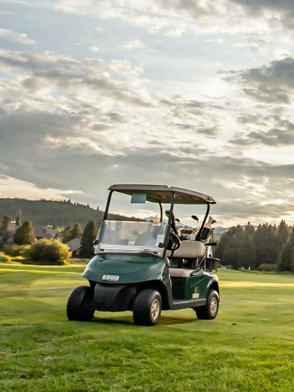 A golfer taking a swing on a golf course while another watches.