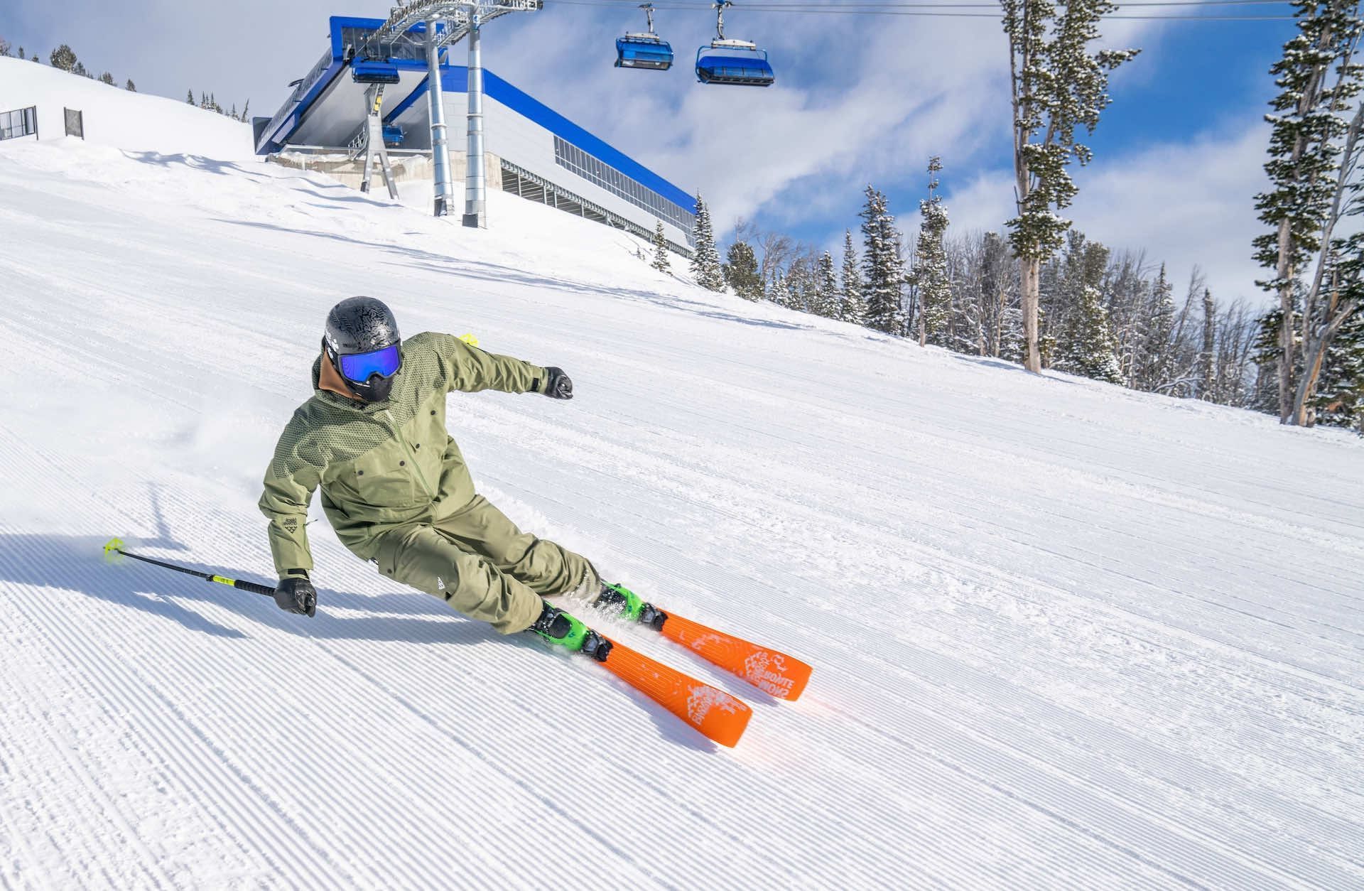 Skier riding a fresh groomed run below a chairlift.