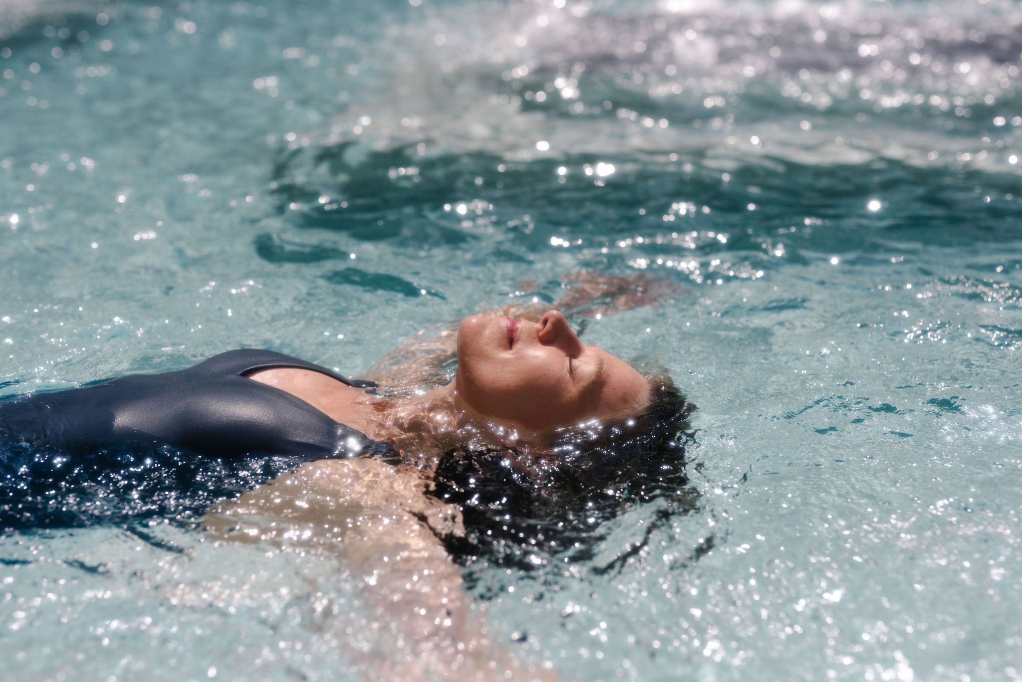 A lady floating on her back, looking very peaceful, in a pool.