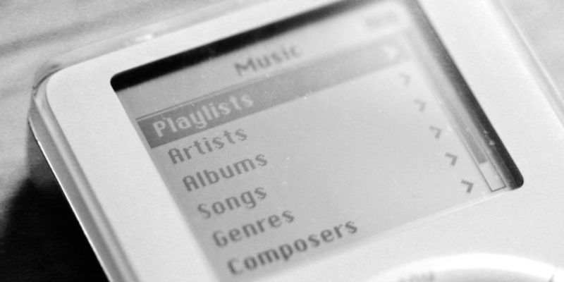 white original iPod with on the screen a music screen with options for playlists, artists, albums, songs, genres and composers