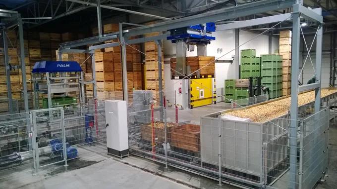 Robot rozładunkowy PALM w hali z drewnianymi skrzyniami i zbiornikiem produktu