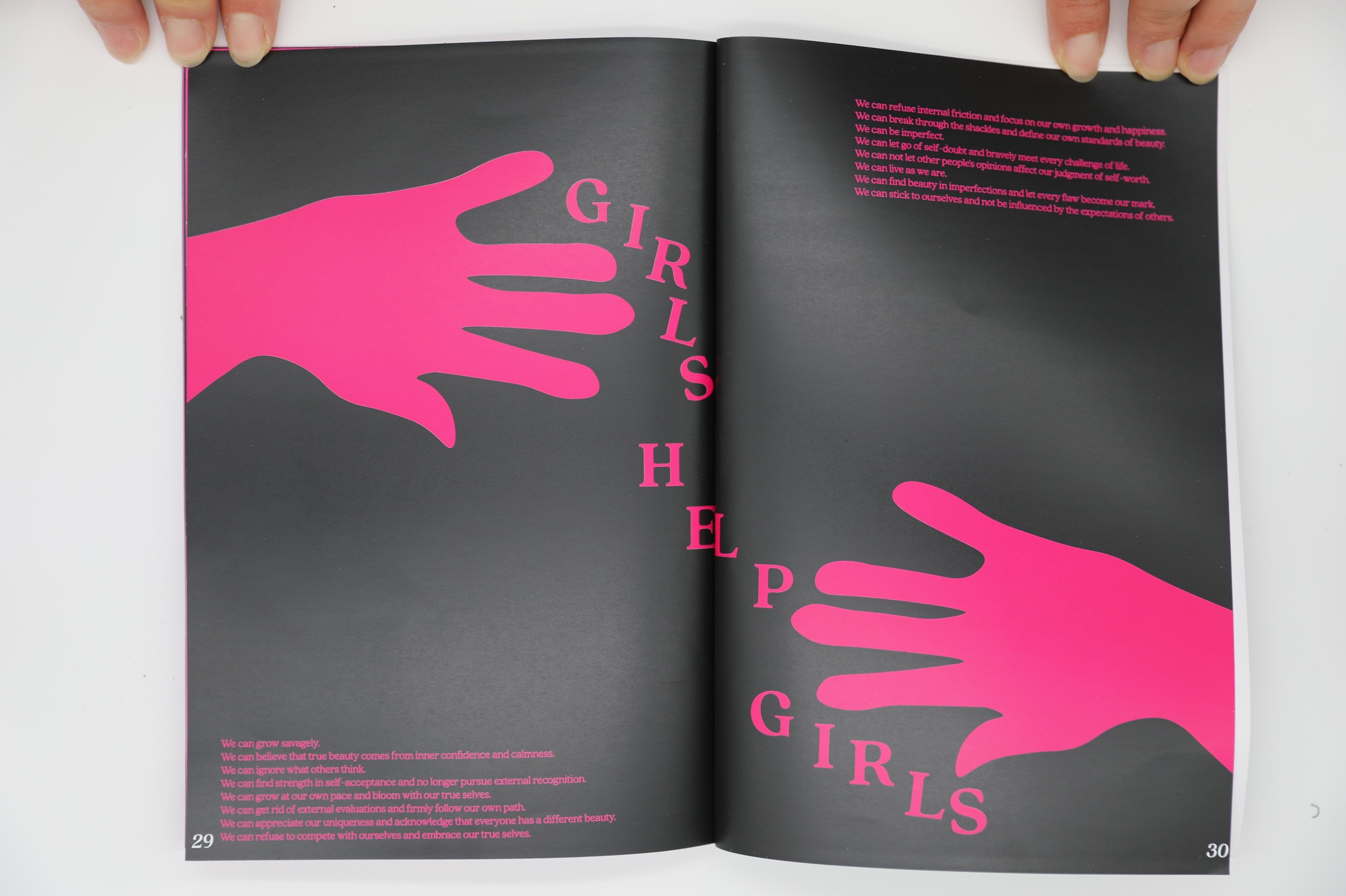 Minimalist art book spread featuring two large pink hand shapes extending across a black background with the words 'Girls Help Girls' arranged between the hands. Small text at the bottom encourages self-acceptance, confidence, and rejecting external judgments.