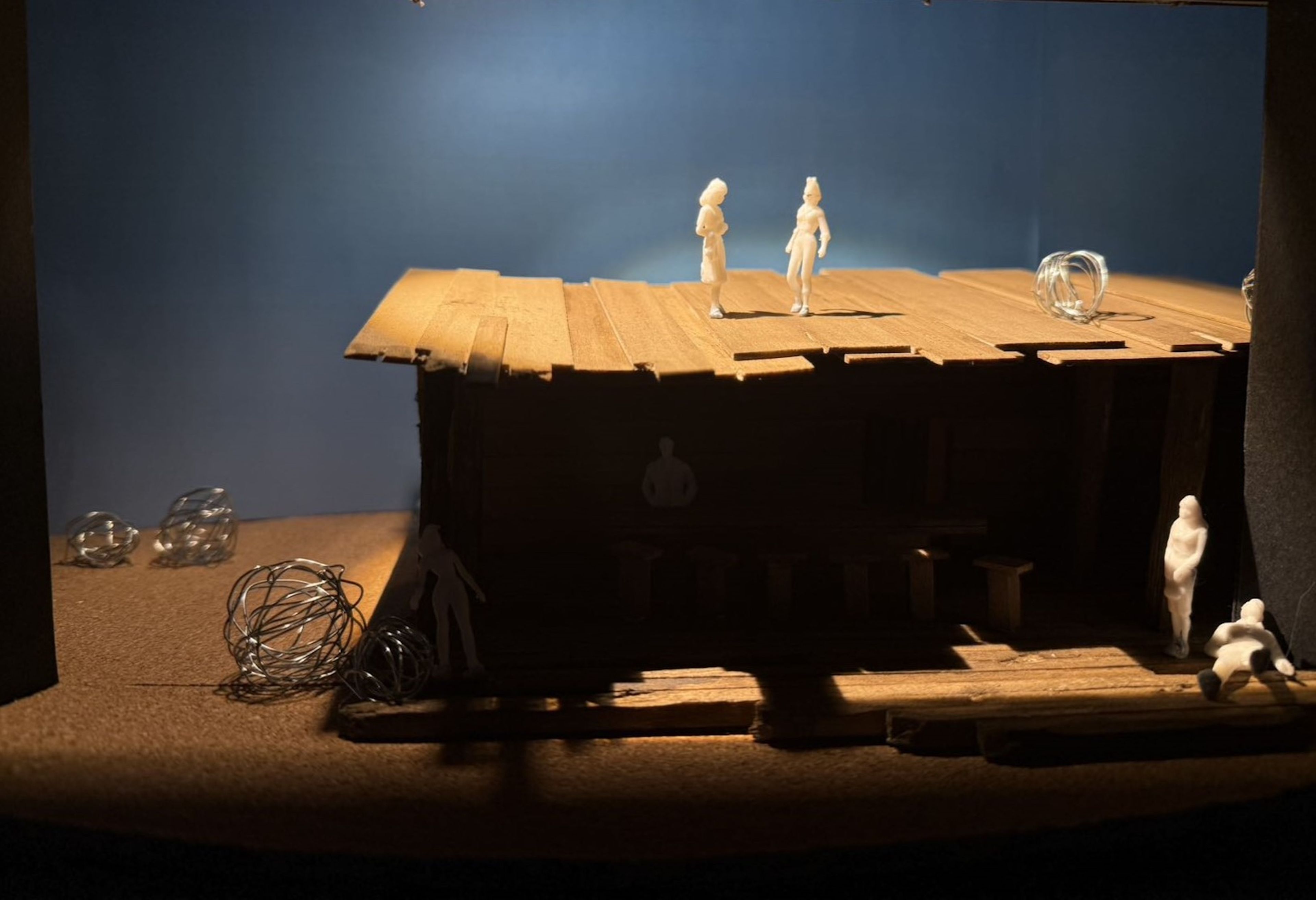 Wooden saloon model set with two figures standing on the roof and others positioned around the entrance and interior.