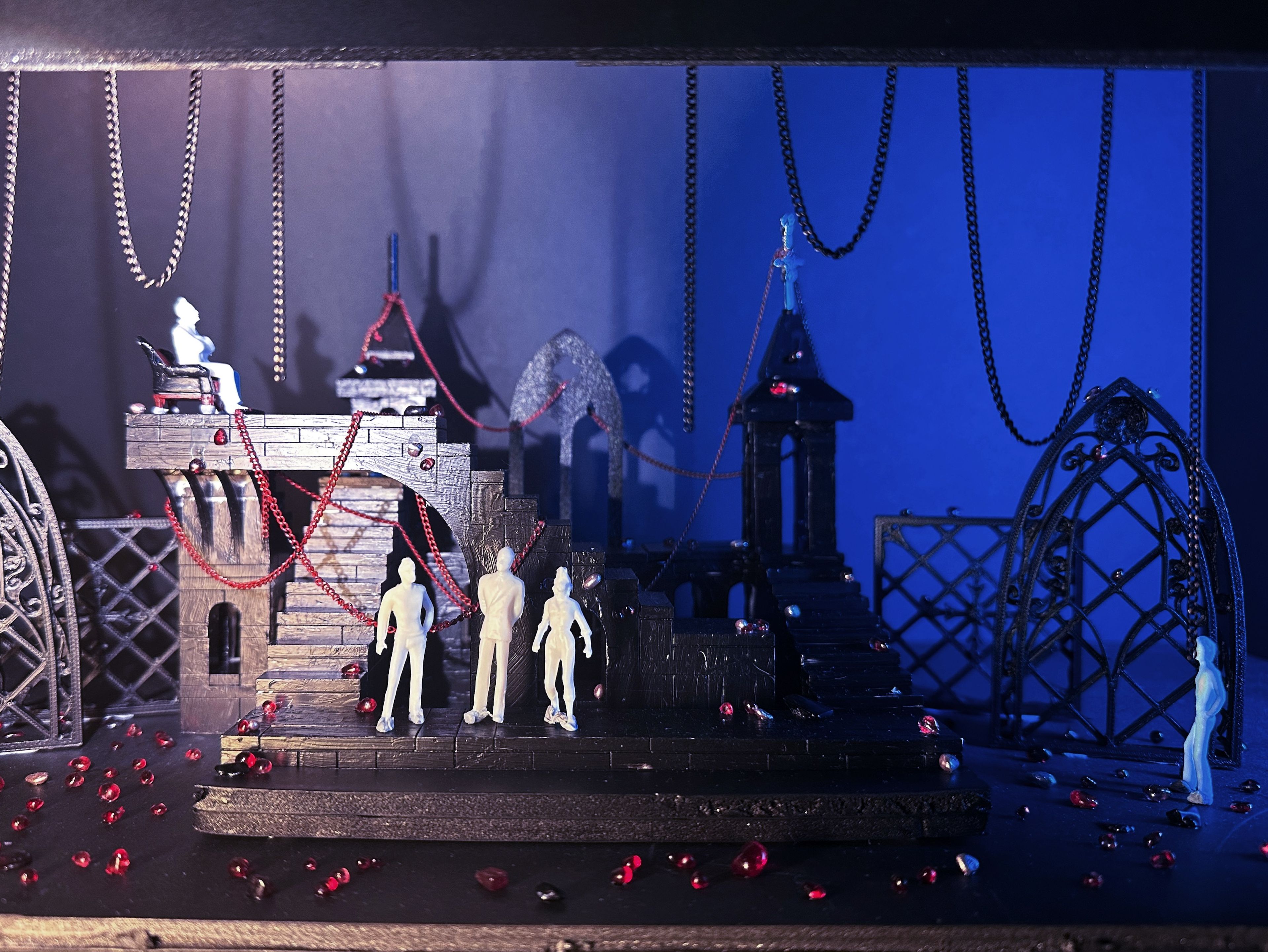 Gothic set model illuminated in blue light, featuring gothic arches, chains, red beads, and white figures on staircases.