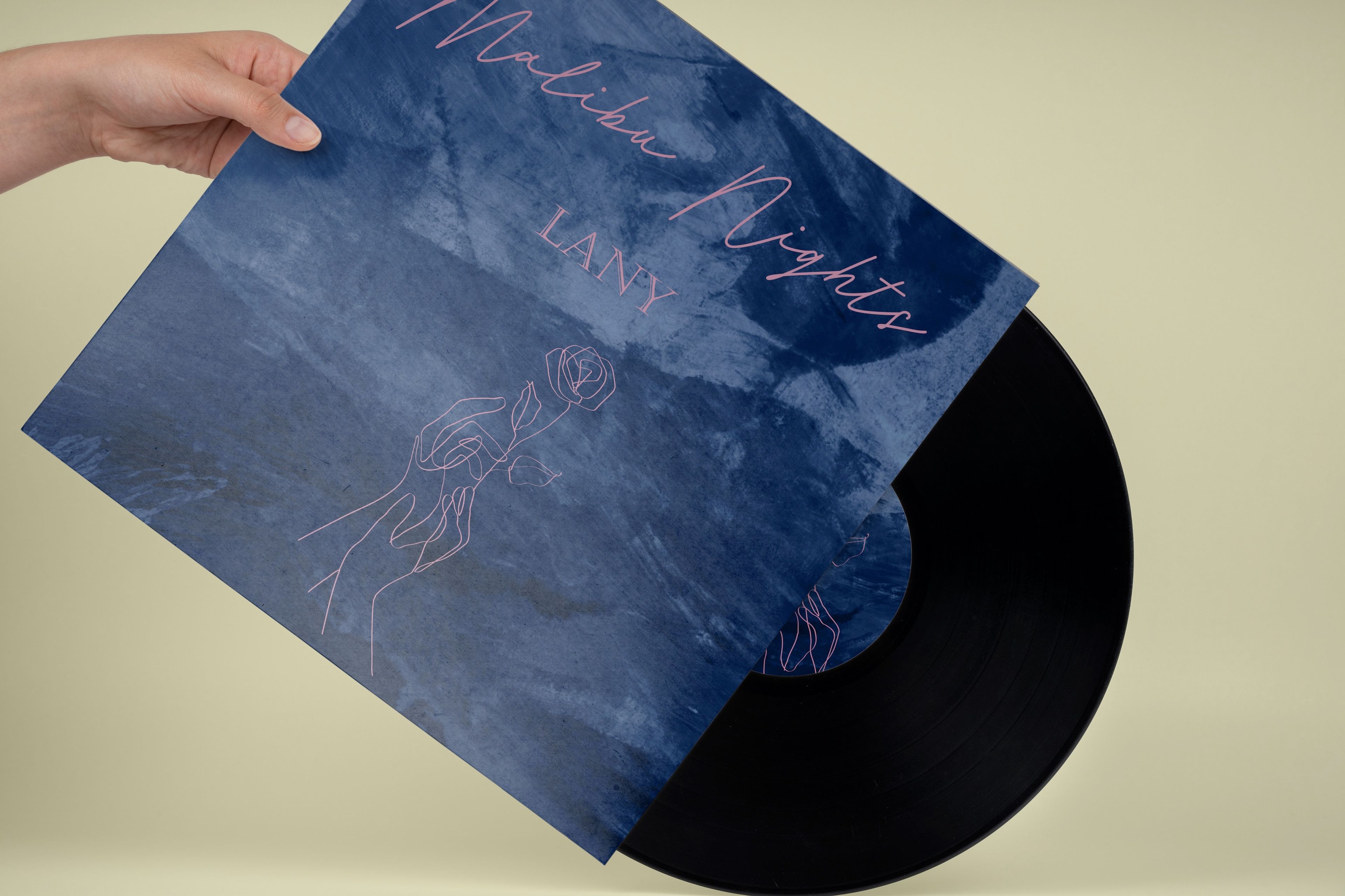 Vinyl record cover for 'Malibu Nights' by LANY, with a deep blue background and pink line art of hands holding a rose. Title is written in cursive.