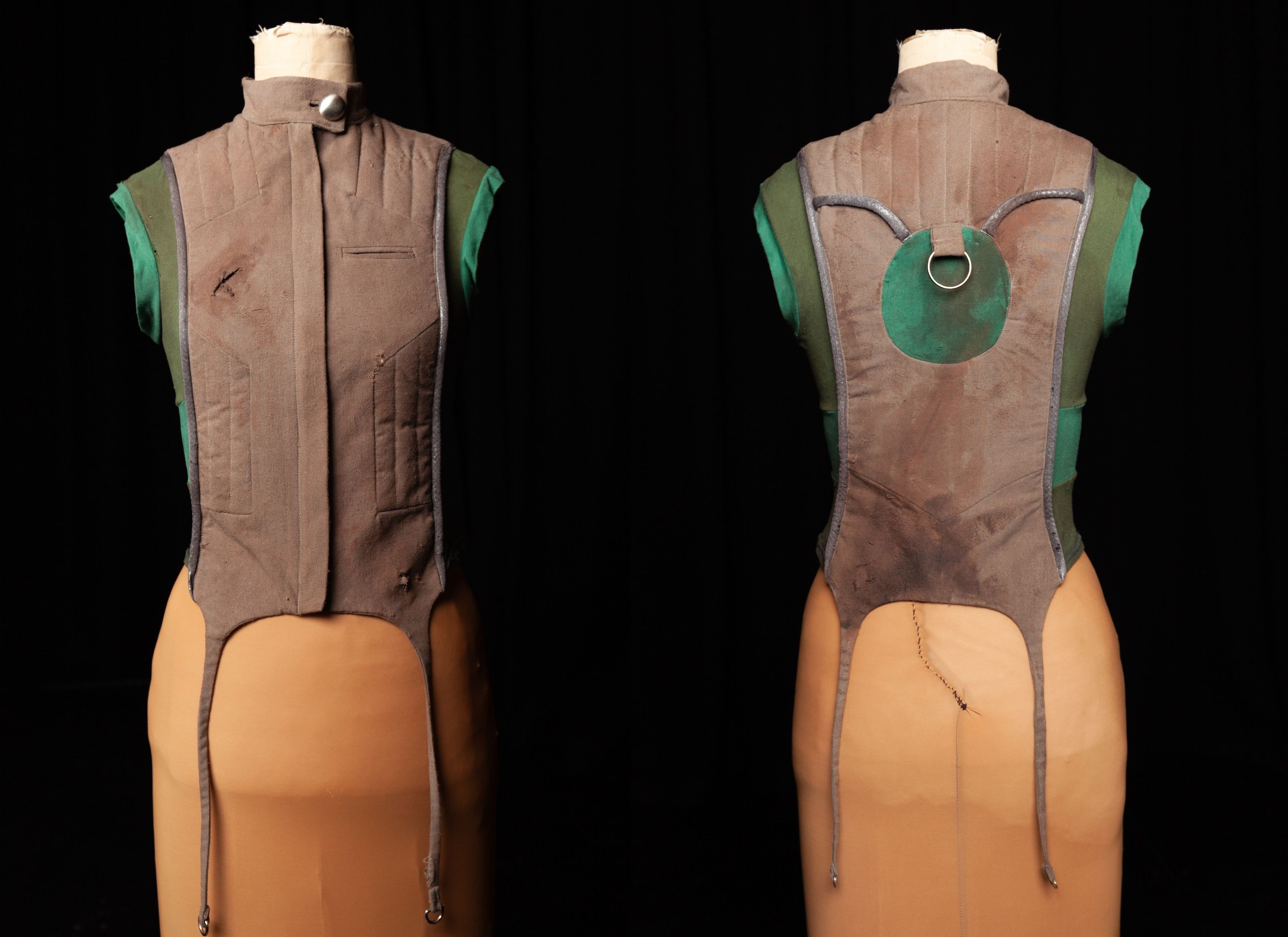 Photograph showing front and back views of a brown and green waistcoat with tails on a mannequin, featuring metal ring detail on the back panel.