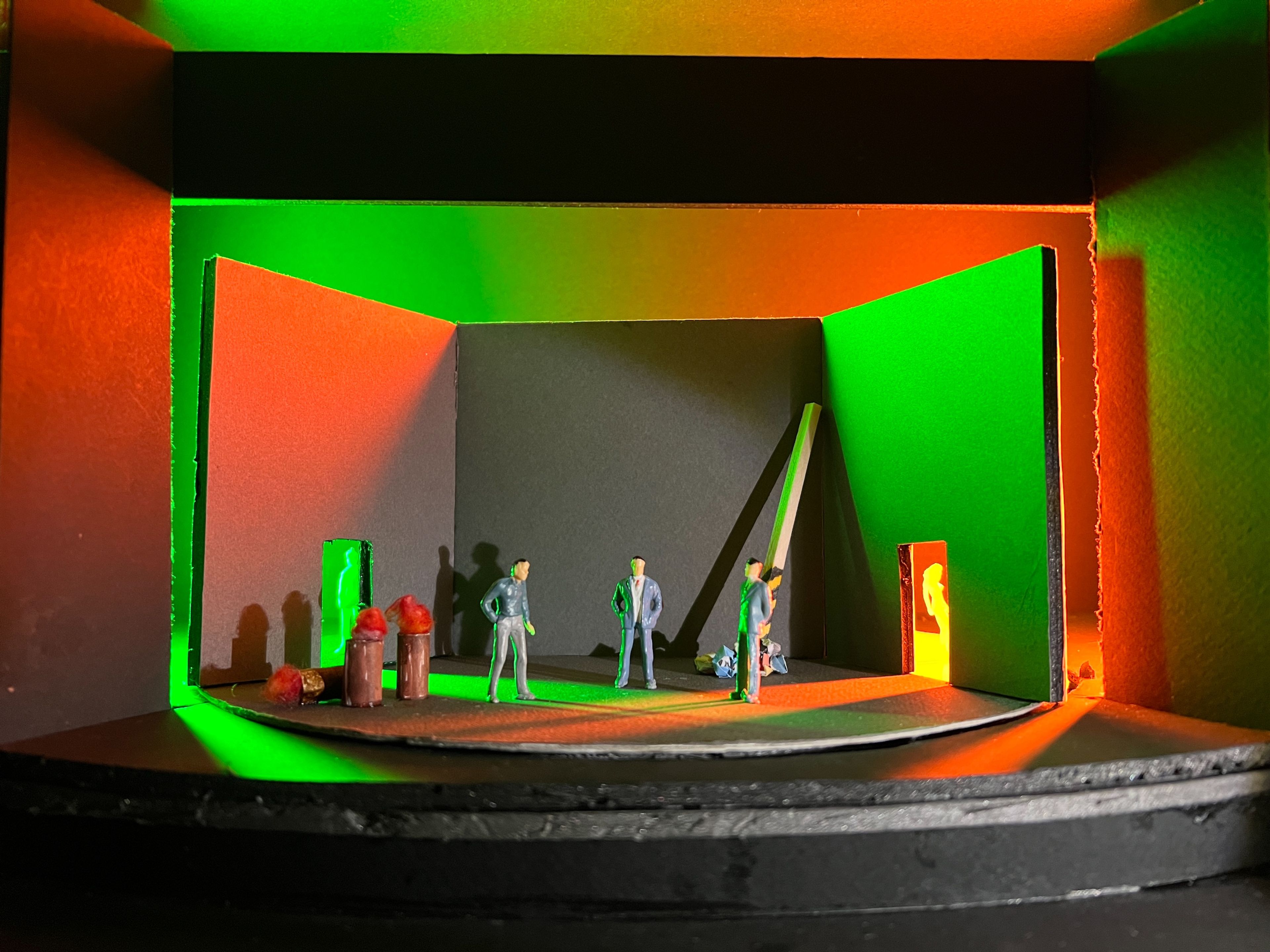 Scale model of a theatre set for Act 1, Scene 1, with figures arranged under green and orange lighting, evoking an ominous atmosphere.