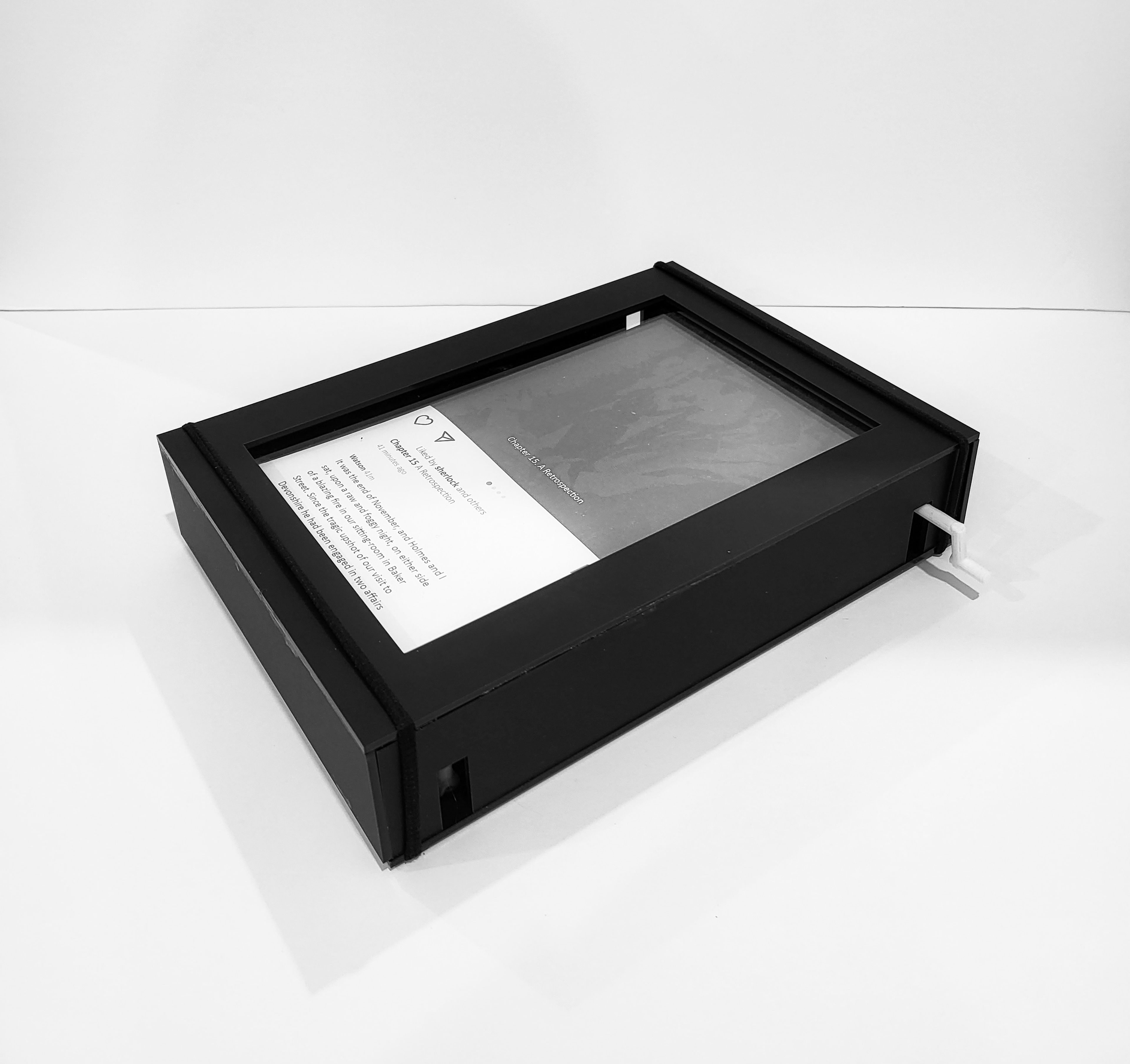 Minimalist black box frame housing documents, photographed in stark monochrome against white background.