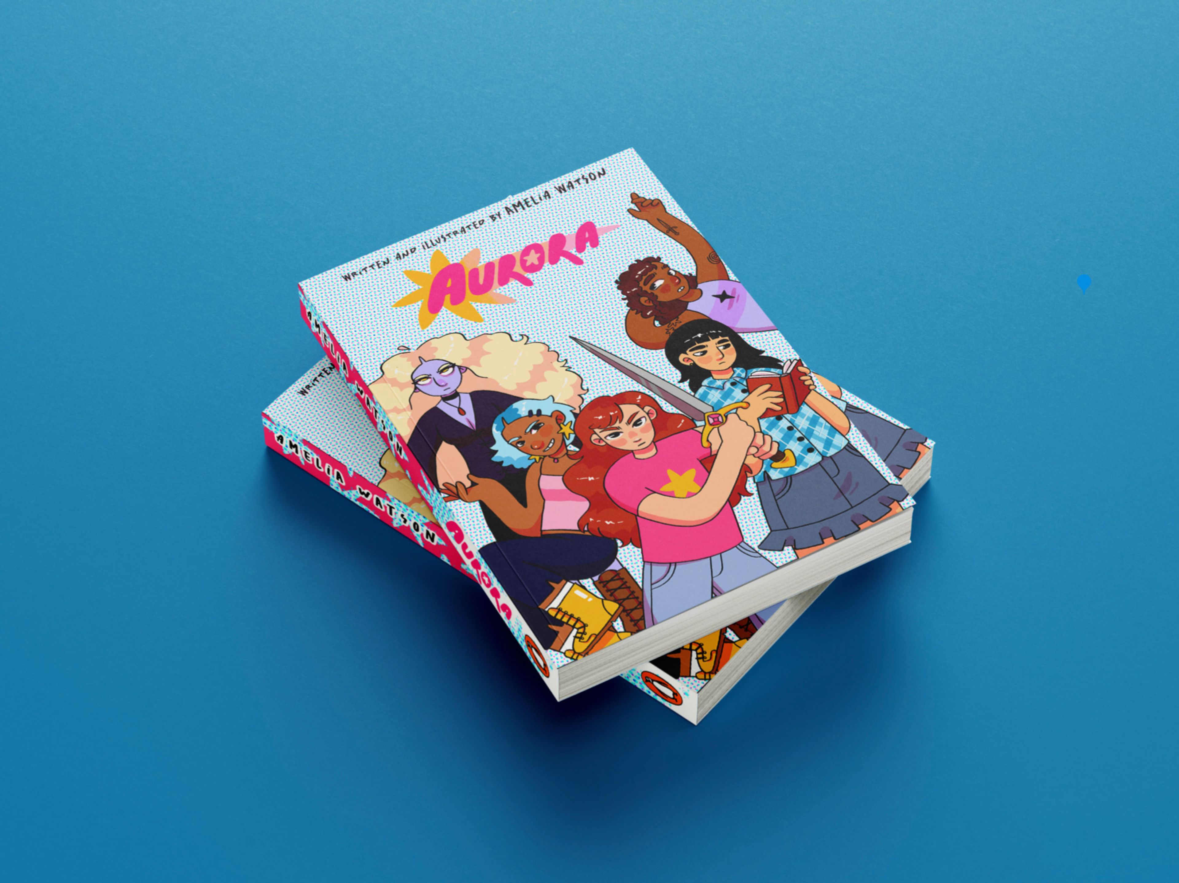 Two stacked graphic novels titled "Aurora" lie on a blue surface. The colourful cover illustration features a diverse group of five characters, each striking a confident pose, with bold, stylised art