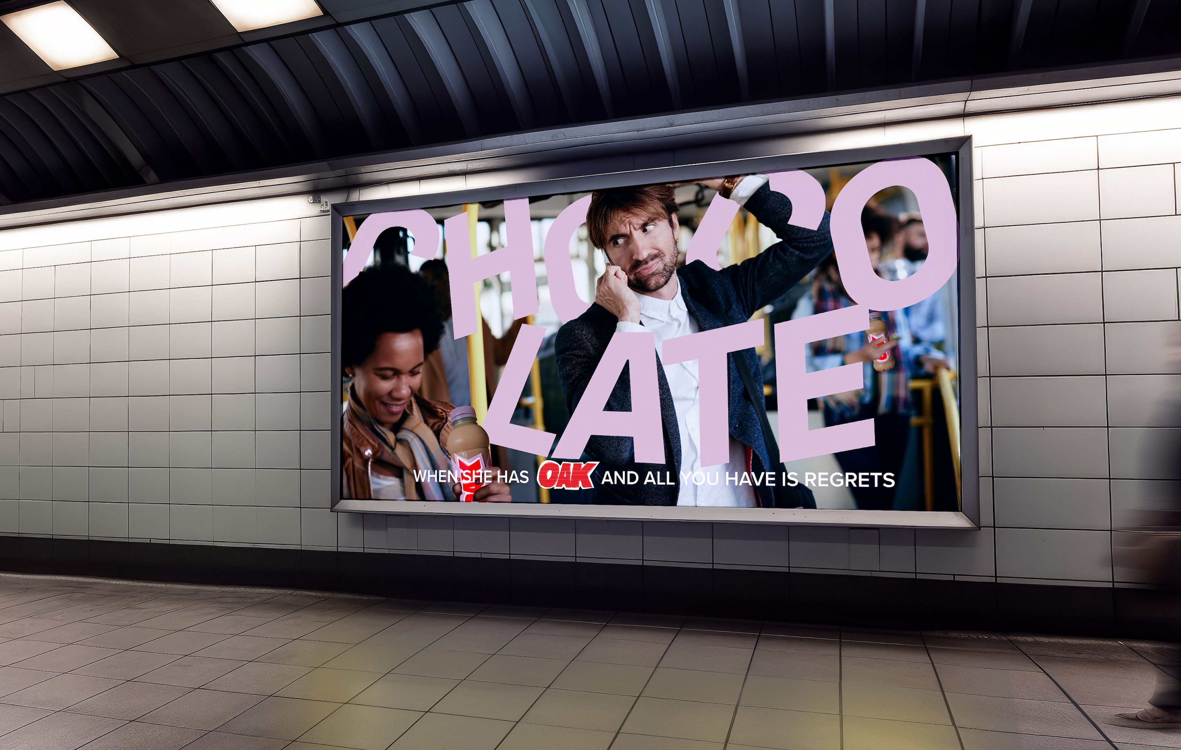 Subway wall display with a large billboard ad showing a man holding his head while a smiling woman holds an Oak milk drink. The word "Chocolate" is partially obscured, with smaller text reading, "When she has Oak and all you have is regrets."