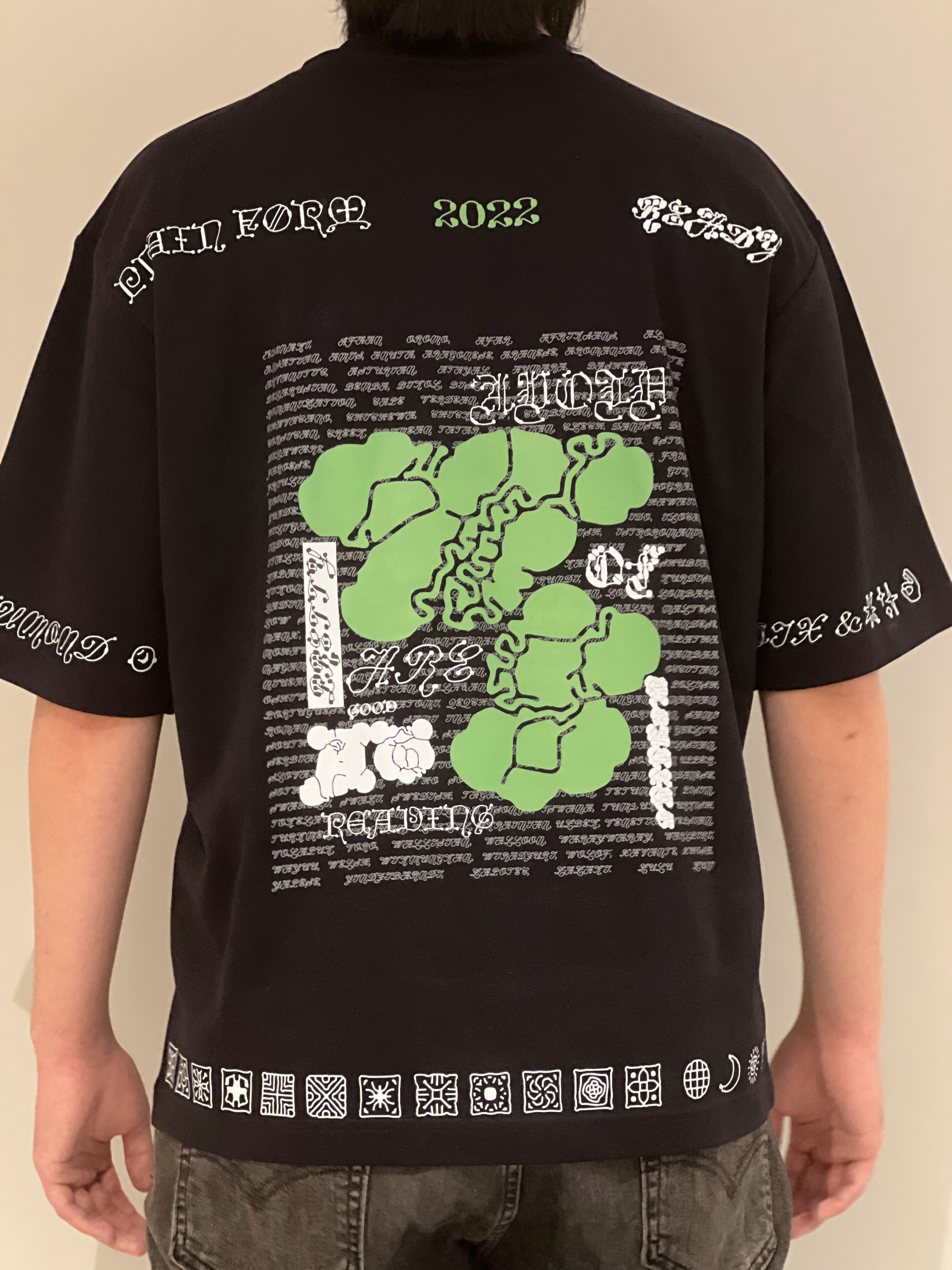 T-shirt design featuring abstract green organic shapes against black fabric. Includes decorative typography and ornamental symbols along bottom border, with '2022' detail highlighted in green.