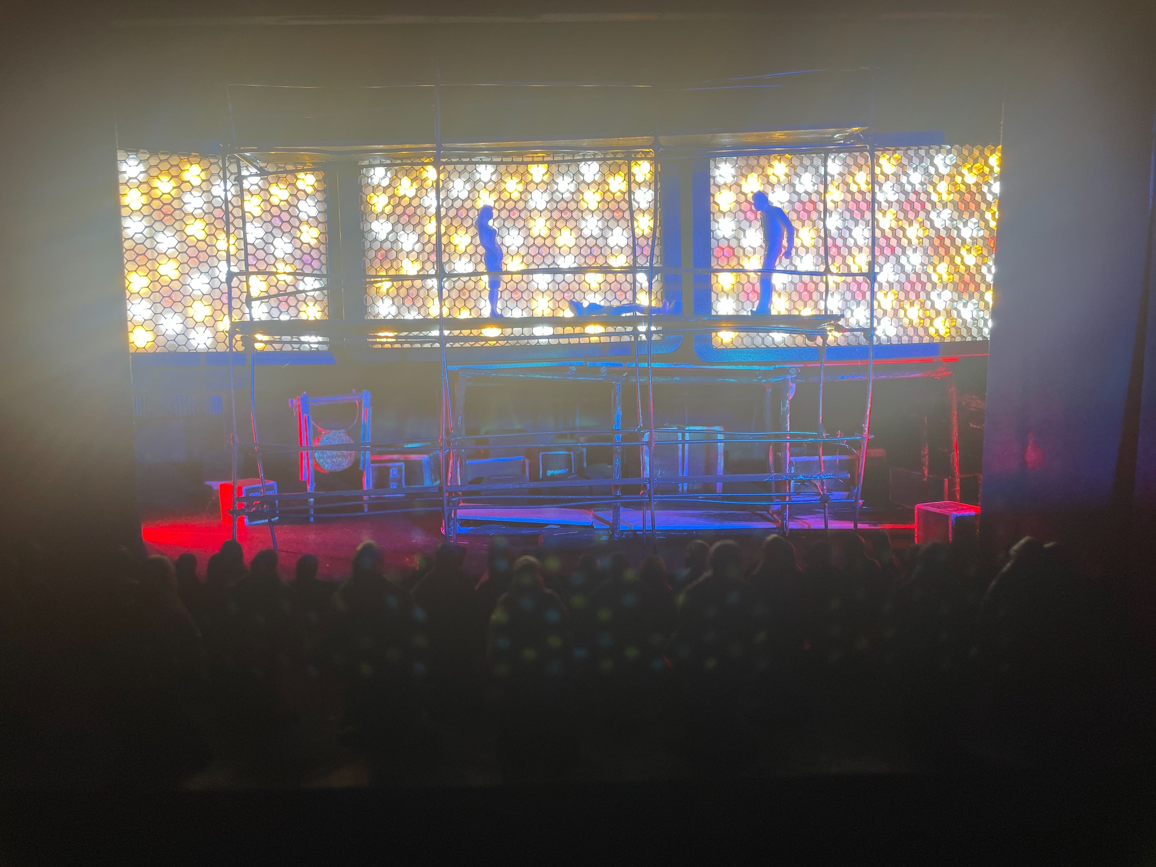 Scale model of a set design with scaffolding and colourful, honeycomb-patterned backlighting.