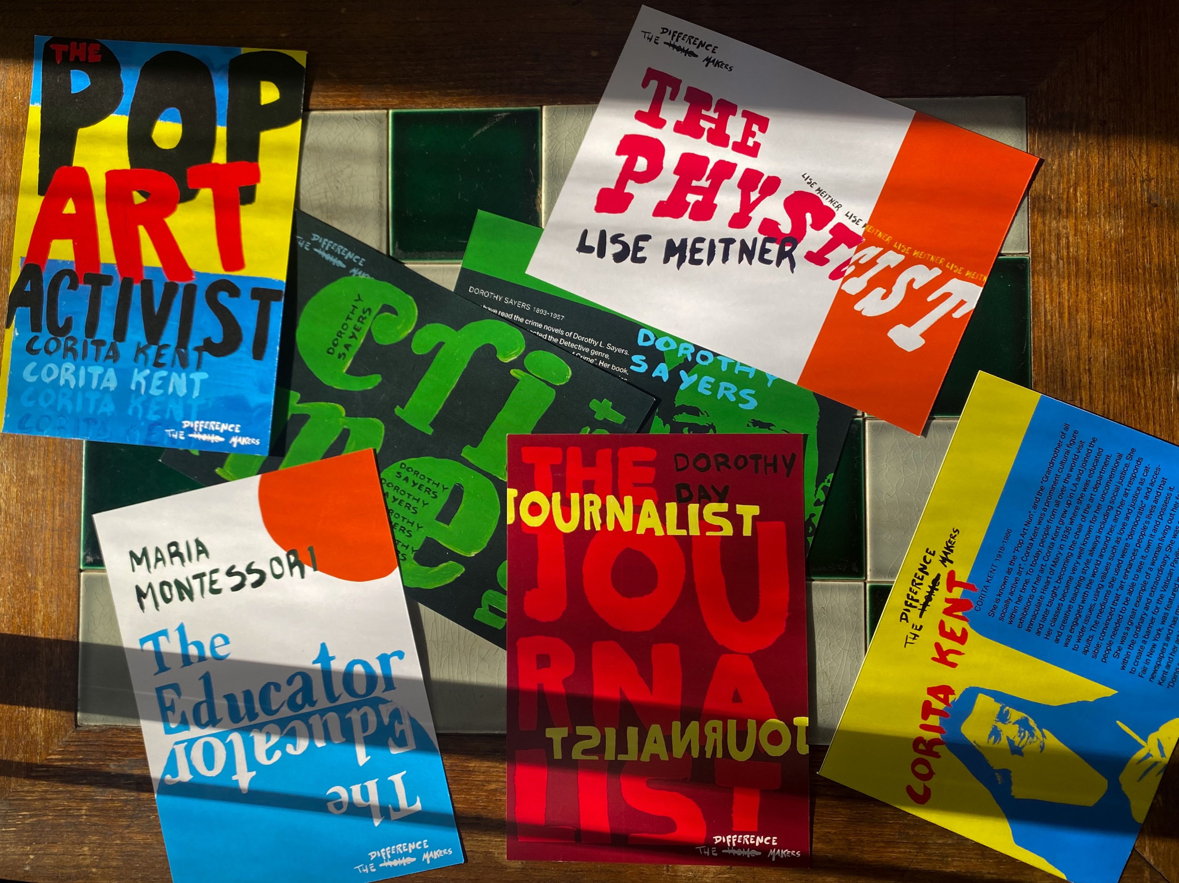 Collection of book covers from 'The Difference Makers Series' featuring influential women, including 'The Pop Art Activist' (Corita Kent), 'The Physicist' (Lise Meitner), 'The Educator' (Maria Montessori), and 'The Journalist' (Dorothy Sayers). Each cover uses bold typography and distinct colour schemes to represent different disciplines.